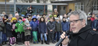 Landrat Christian Engelhardt spricht mit einem Mikro zu einer großen Gruppe Kinder