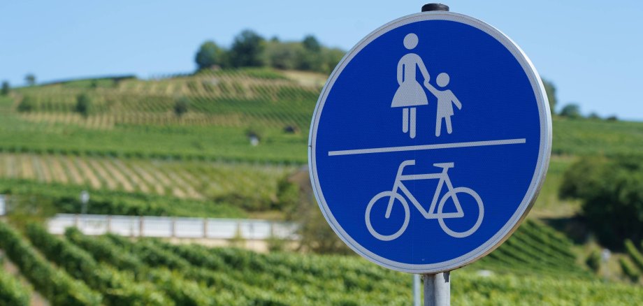 Ein Verkehrsschild für Fußgänger und Radfahrer mit Weinbergen im Hintergrund