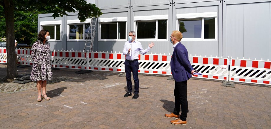 Landrat Christian Engelhardt (Mitte) nahm gemeinsam mit Johannes Kühn vom Eigenbetrieb Schule und Gebäudewirtschaft (rechts) und Silke Weimar-Ekdur (links), der Schulleiterin des Lessing-Gymnasiums Lampertheim, das neue Übergangsschulgebäude in Augenschein, während dieses aufgestellt wurde.