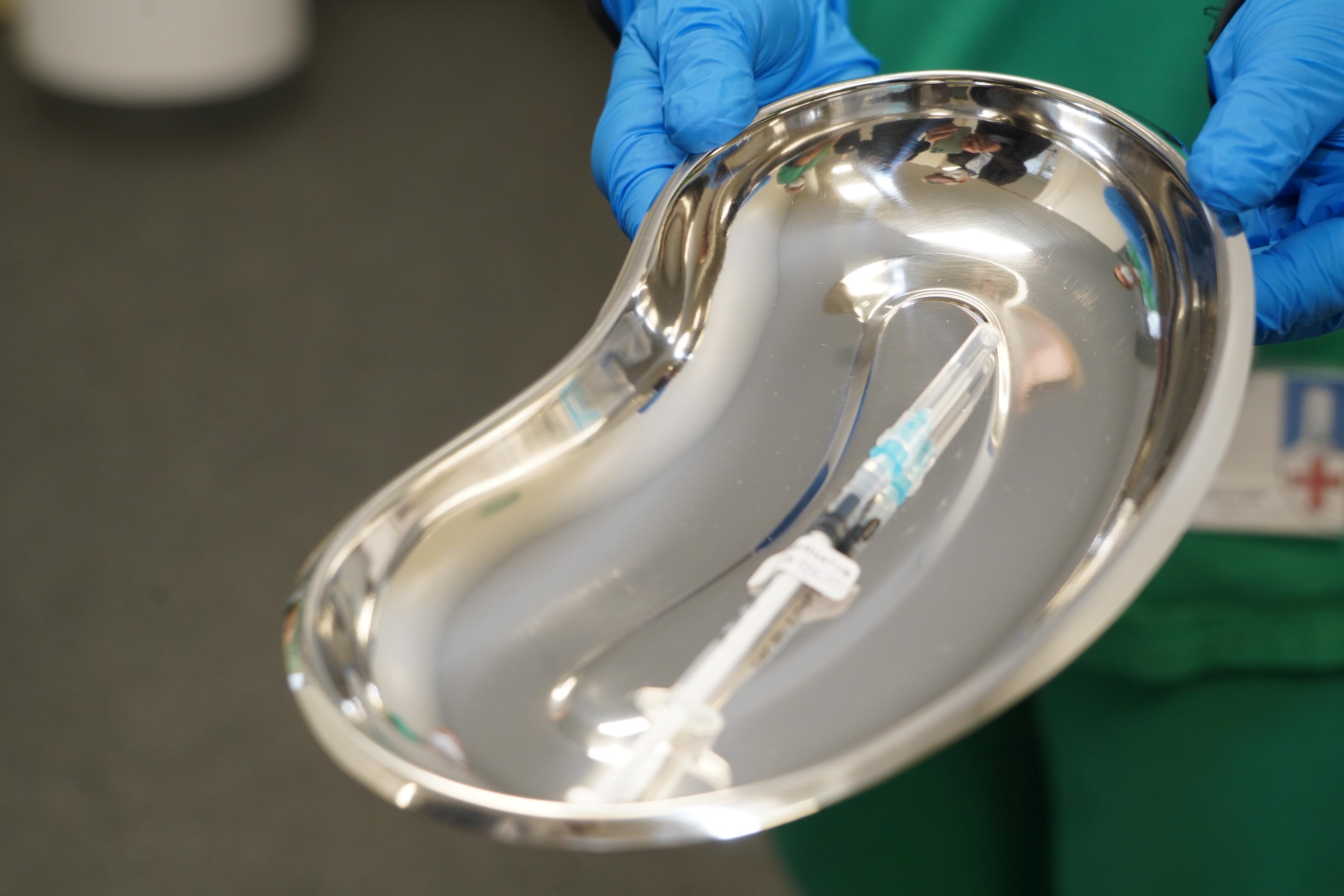 In einer silbernen Schale liegt eine aufgezogene Spritze zur Impfung bereit