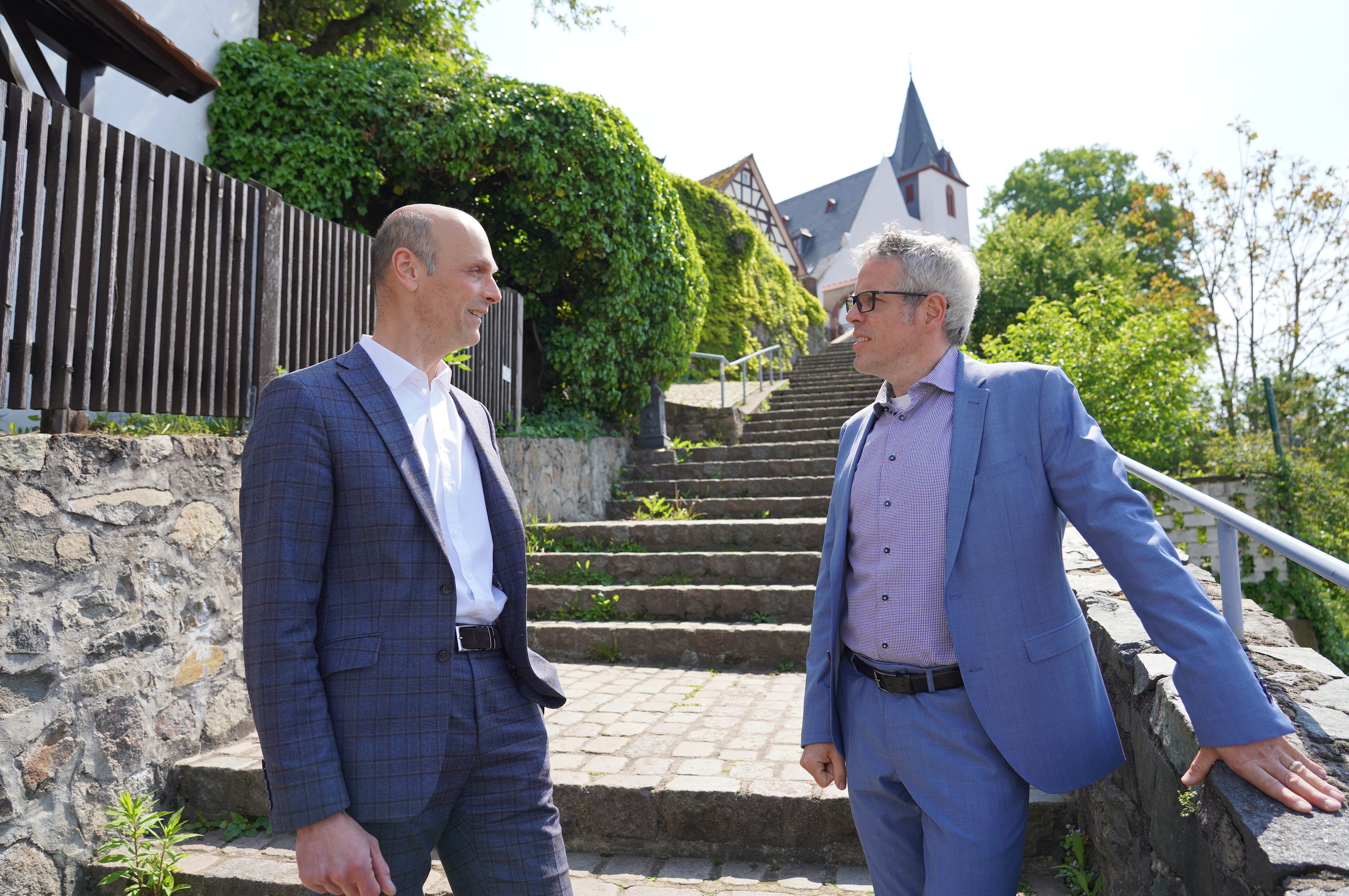 Rundgang durch Zwingenberg: Landrat Christian Engelhardt (re.) und Bürgermeister Dr. Holger Habich stehen im Freien an einer Treppe in Zwingenberg.