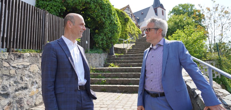 Rundgang durch Zwingenberg: Landrat Christian Engelhardt (re.) und Bürgermeister Dr. Holger Habich stehen im Freien an einer Treppe in Zwingenberg.