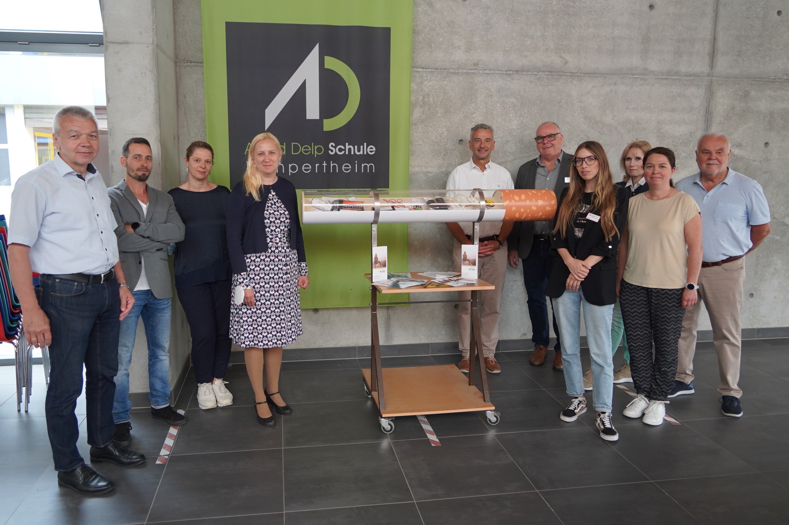 Das Bild zeigt ein Gruppenfoto von Menschen, die sich um eine große Modellzigarette versammeln. Das Modell  haben Schüler und Schülerinnen der Heinrich-Metzendorf-Schule in Bensheim gebaut. Auf dem Foto zu sehen sind Lampertheims Bürgermeister Gottfried Störmer, Ralf Stadler, Präventionslehrer an der Heinrich-Metzendorf-Schule in Bensheim, Sylvia Meier, Leiterin der Alfred-Delp-Schule in Lampertheim, die Erste Kreisbeigeordnete Diana Stolz, Dr. Karl-Wilhelm Klingler vom Lampertheimer Ärztenetzwerk Gala, Adrian Steier-Bertz, Fachbereichsleiter bei der AWO Prisma Suchthilfe & Prävention, Nikita Girard, Sozialpädagogin bei Prisma, Reinhild Zolg, Präventionsbeauftragte des Kreises Bergstraße, Petra Popp, stellvertretende Schulleiterin der Alfred-Delp-Schule und Andreas Förster von Gala. 