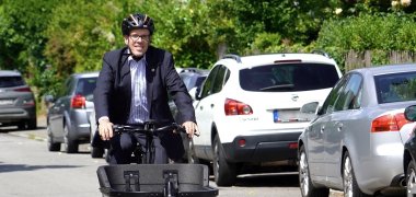 Landrat Christian Engelhardt sitzt auf einem Lastenrad und fährt durch eine Straße in Bensheim.