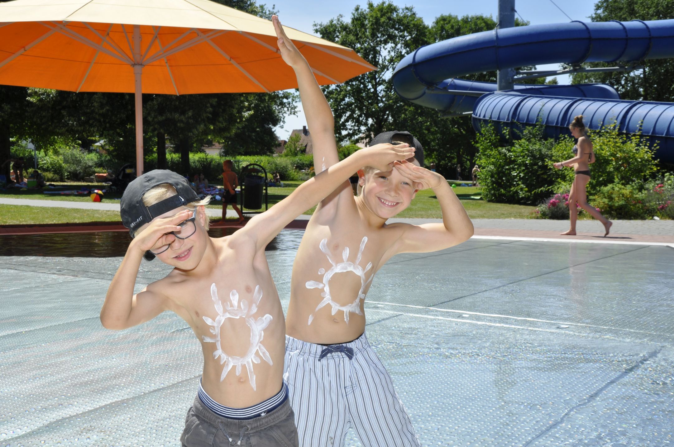 Zwei fröhliche Jungen im Freibad mit Sonnencreme-Sonnen auf dem Bauch