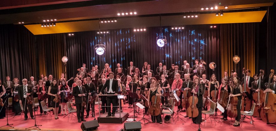Das Bild zeigt das Orchester der Starkenburg Philharmoniker, das gesamte Orchester steht aufgereiht mit Instrumenten da und schaut in die Kamera.