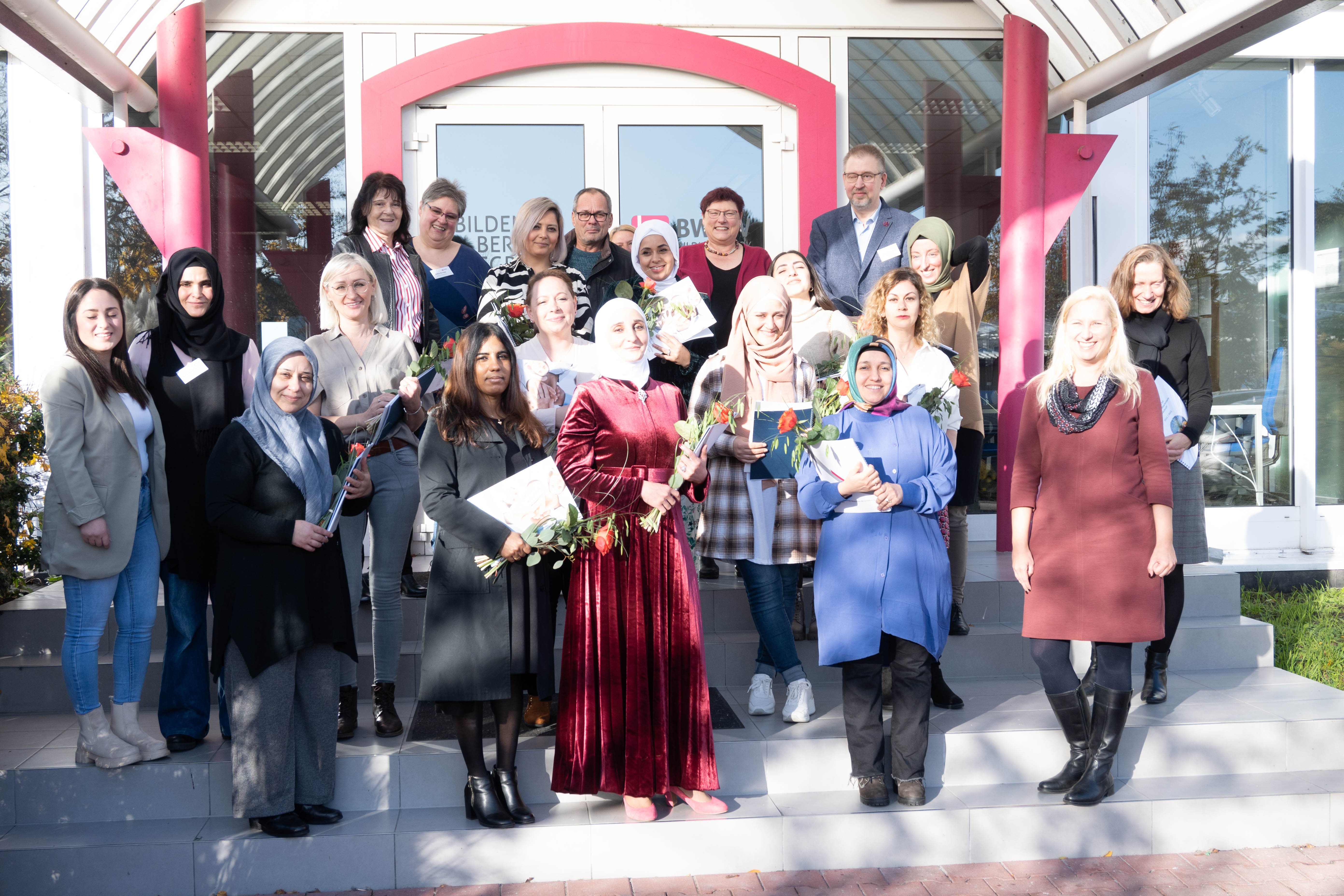 Grund zum Jubel: Die Absolventinnen der Weiterbildungsmaßnahme „Qualifizierung zur pädagogischen Mitarbeiterin als Zusatzkraft“ zusammen mit der Ersten Kreisbeigeordneten Diana Stolz und weiteren Beteiligten vor dem Gebäude des Bildungswerkes der Hessischen Wirtschaft e. V. in Bensheim.