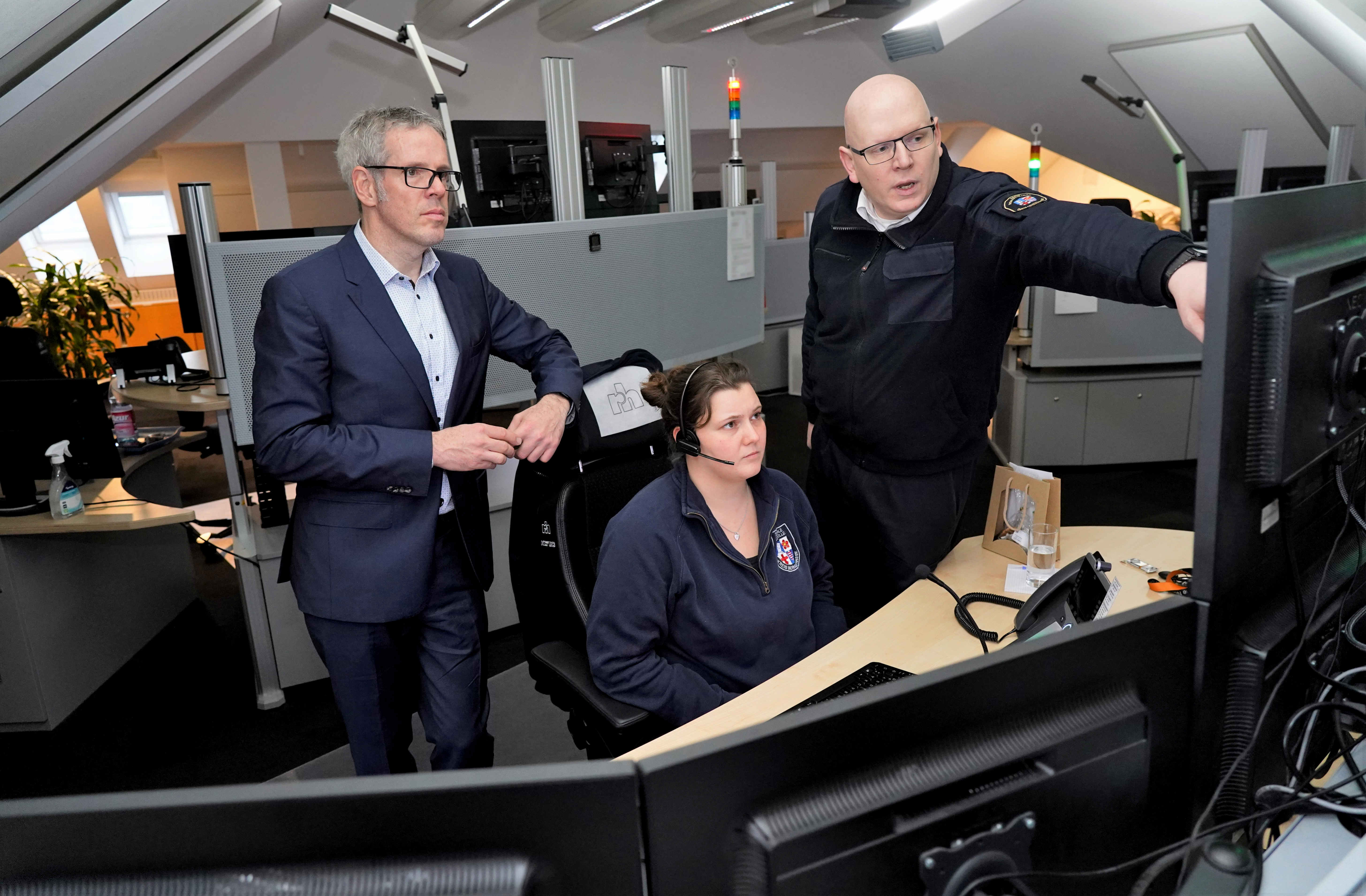 Landrat Christian Engelhardt, Christian Stracke, Leiter Gefahrenabwehr und Jenny Fritz, Mitarbeiterin der Leitstelle, sehen sich die aktuelle Lage an einem PC in der Leitstelle an.