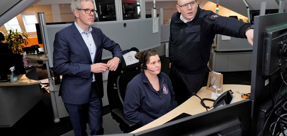 Landrat Christian Engelhardt, Christian Stracke, Leiter Gefahrenabwehr und Jenny Fritz, Mitarbeiterin der Leitstelle, sehen sich die aktuelle Lage an einem PC in der Leitstelle an.