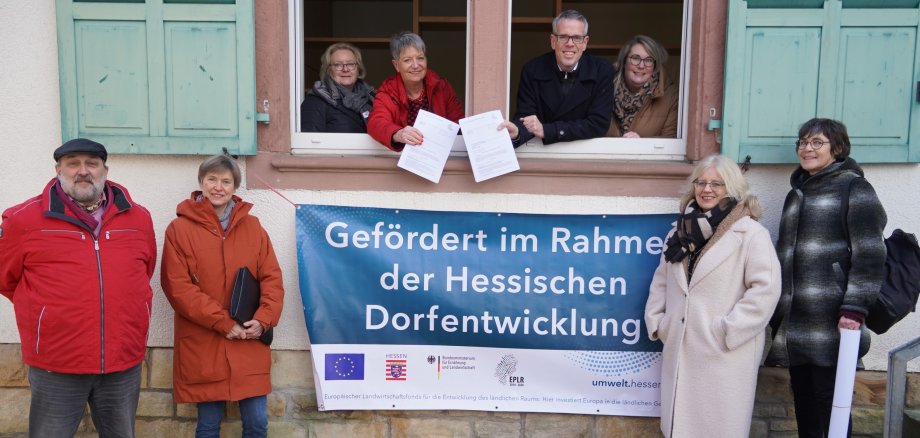 Landrat Christian Engelhardt (4. v. re.) überreichte an der Alten Schule in Hochstädten Bensheims Bürgermeisterin Christine Klein (4.v.li.) im Rahmen des Dorfentwicklungsprogrammes des Landes Hessen zwei Förderbescheide. Mit auf dem Bild von links nach rechts: Ernst Seeger (Fachbereichsleiter Dorferneuerung und Regionalentwicklung in der Kreisverwaltung), Jutta Scheurich (stellvertretende Leiterin des Teams Stadtplanung, Mobilität und Demographie der Stadt Bensheim), die Erste Stadträtin von Bensheim Nicole Rauber-Jung (im Fenster), Christina Müller (Sachbearbeiterin Dorferneuerung und Regionalentwicklung in der Kreisverwaltung, im Fenster), Birgit Kiemle (Architektin im Eigenbetrieb Kinderbetreuung Stadt Bensheim), Dorothea Aßmann (stellvertretende Leiterin des Eigenbetriebes Kinderbetreuung der Stadt Bensheim).