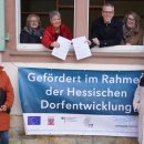 Landrat Christian Engelhardt (4. v. re.) überreichte an der Alten Schule in Hochstädten Bensheims Bürgermeisterin Christine Klein (4.v.li.) im Rahmen des Dorfentwicklungsprogrammes des Landes Hessen zwei Förderbescheide. Mit auf dem Bild von links nach rechts: Ernst Seeger (Fachbereichsleiter Dorferneuerung und Regionalentwicklung in der Kreisverwaltung), Jutta Scheurich (stellvertretende Leiterin des Teams Stadtplanung, Mobilität und Demographie der Stadt Bensheim), die Erste Stadträtin von Bensheim Nicole Rauber-Jung (im Fenster), Christina Müller (Sachbearbeiterin Dorferneuerung und Regionalentwicklung in der Kreisverwaltung, im Fenster), Birgit Kiemle (Architektin im Eigenbetrieb Kinderbetreuung Stadt Bensheim), Dorothea Aßmann (stellvertretende Leiterin des Eigenbetriebes Kinderbetreuung der Stadt Bensheim).