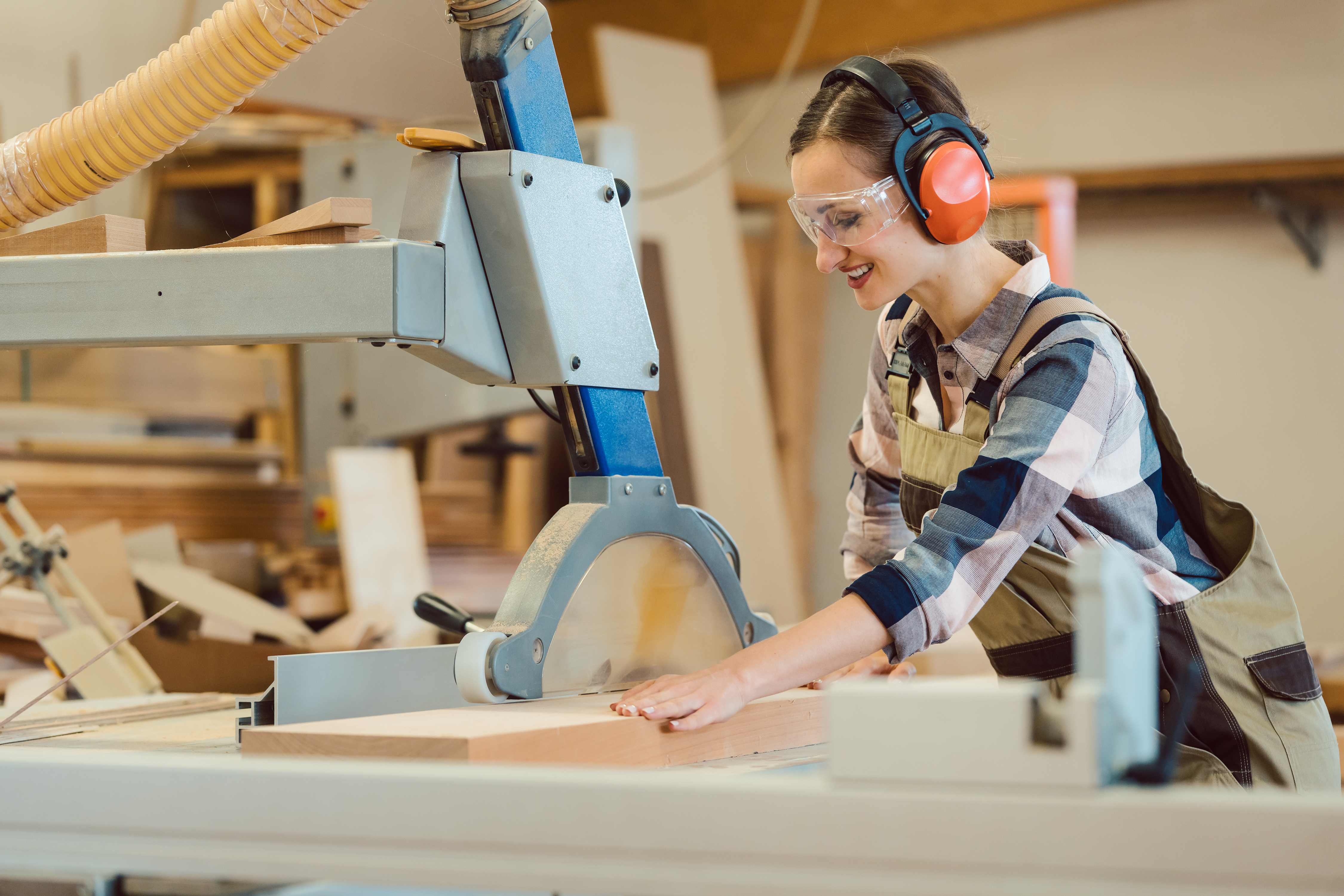 Woman carpenter working with wood at the table saw