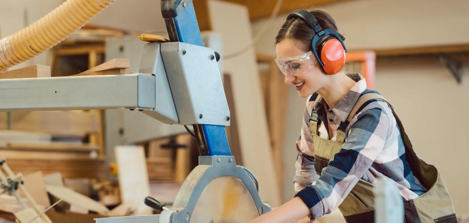 Woman carpenter working with wood at the table saw