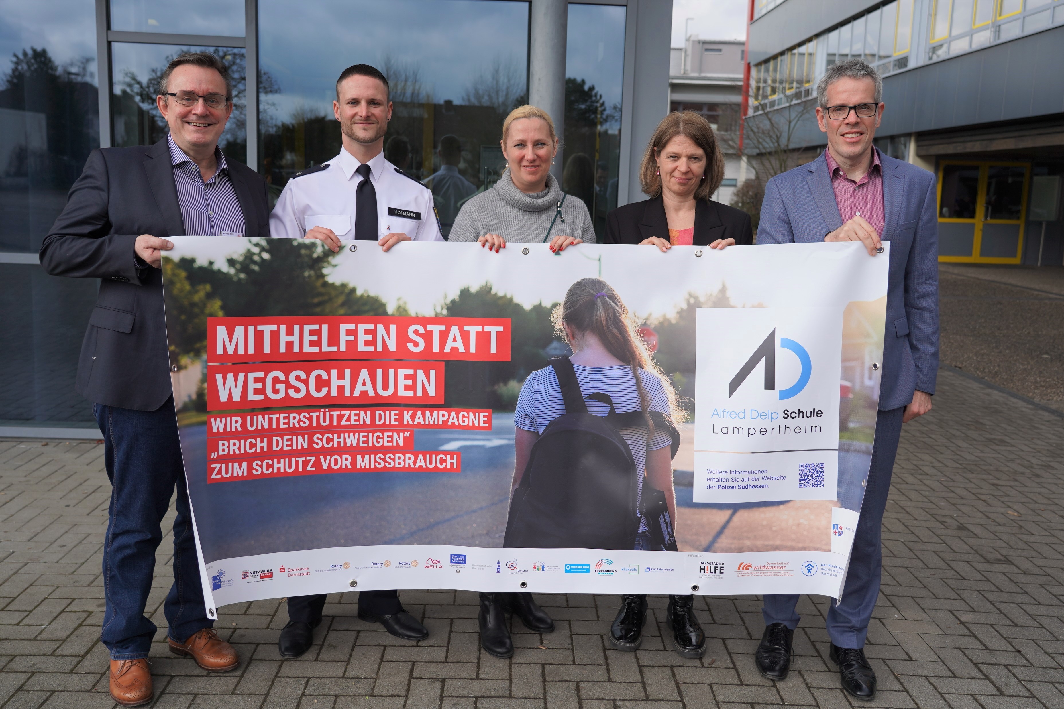 Gemeinsam gegen sexuellen Missbrauch: Landrat Christian Engelhardt, die Leiterin der Alfred-Delp-Schule Sylvia Meier, die Erste Kreisbeigeordnete Diana Stolz, der Jugendkoordinator der Polizeidirektion Bergstraße Johannes Emanuel Hofmann und Kriminalhauptkommissar Michael Rühl (v.r.n.l.) mit dem Banner der Kampagne „Brich Dein Schwiegen – hinter jedem Missbrauch steckt ein Gesicht“.