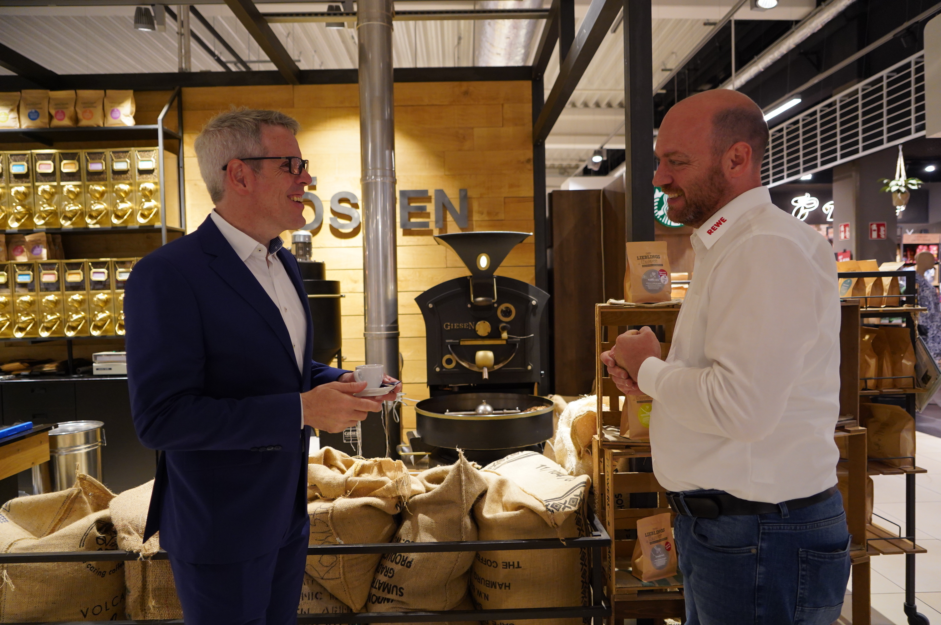 Landrat Christian Engelhardt (links) und Daniel Ludorf (rechts) testen auf dem Bild den selbst vor Ort gerösteten Kaffee.