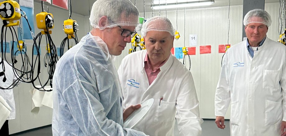 Die Geschäftsführer der CAT Europa Catering GmbH, Sven Podszus (rechts) und Jürgen Helfrich (Mitte), präsentieren Landrat Christian Engelhardt die verzehrbereiten Speisen, die an die Schulen und Kindertagesstätten geliefert werden. 