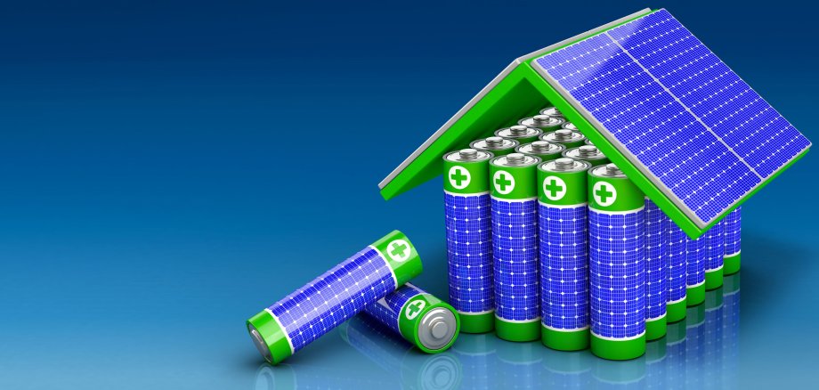 Das Bild zeigt Batterien, die zusammenstehen und so mit einem Solardach ein Haus ergeben - als Symbol für Energiespeicher.