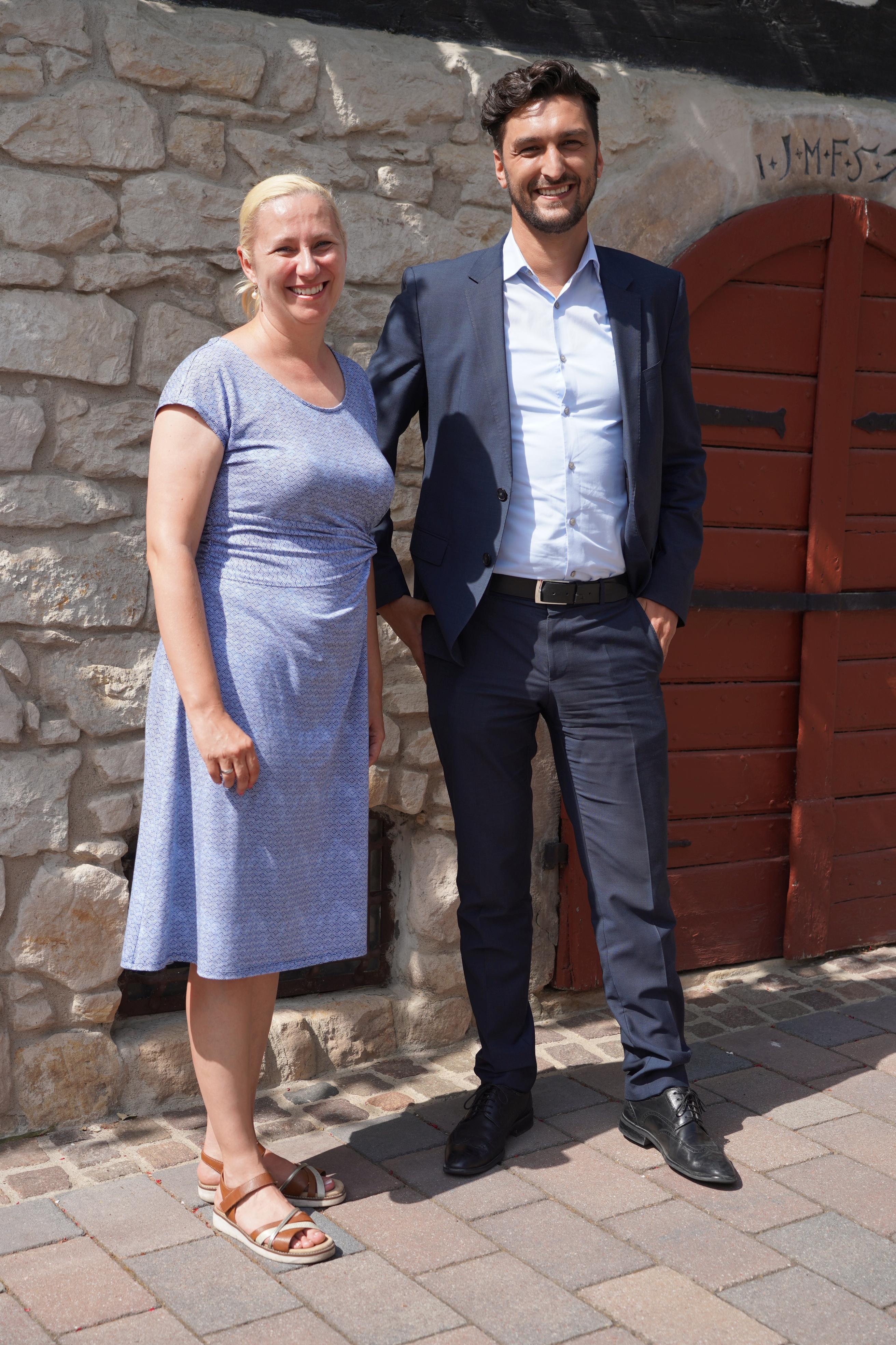 Die Erste Kreisbeigeordnete und Gesundheitsdezernentin Diana Stolz und der neue Klinikgeschäftsführer der Schön Klinik Lorsch, Martin Wiesel, stehen gemeinsam vor einer Steinwand und lächeln in die Kamera. 