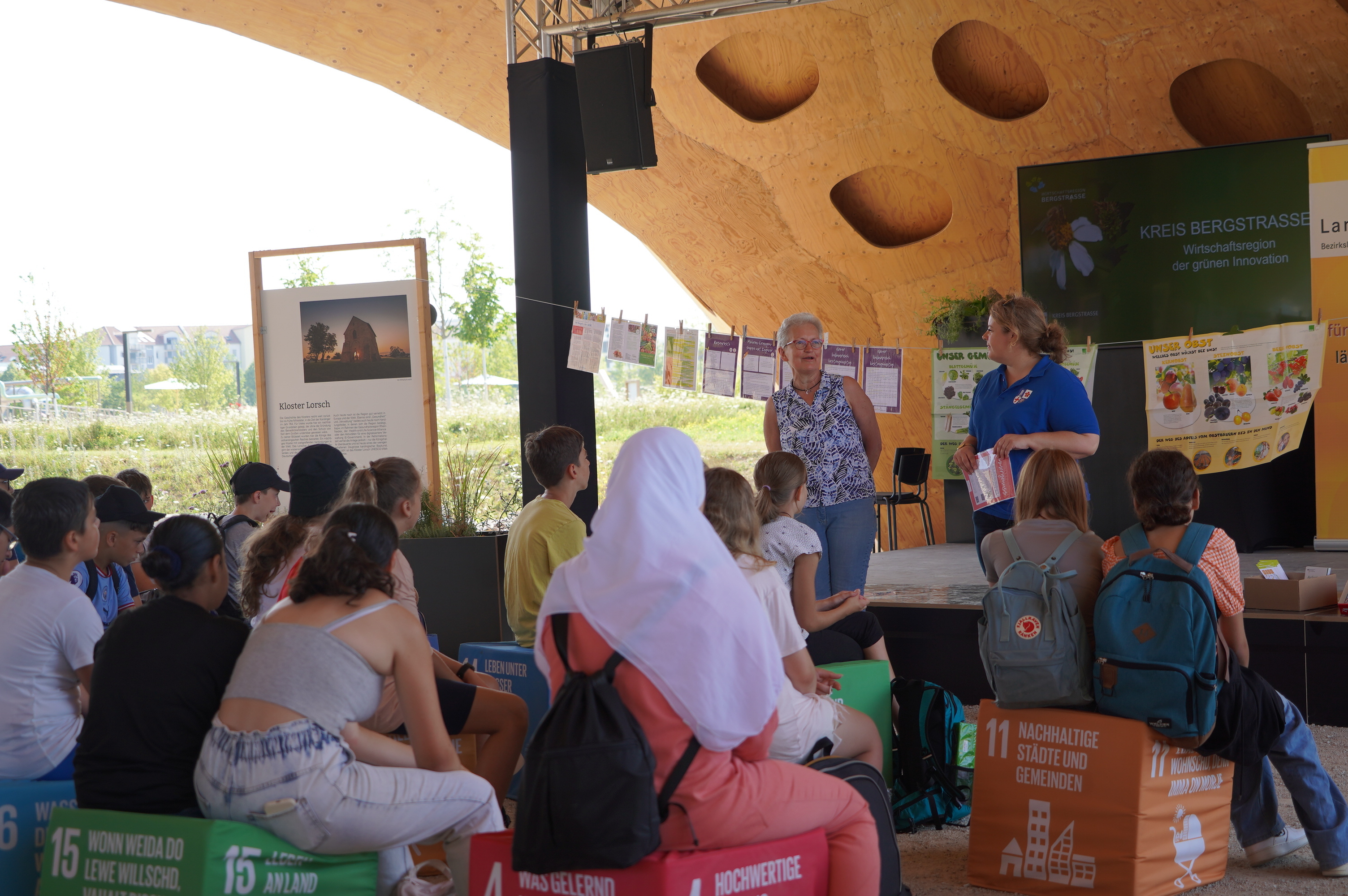 Frau Billau, die Vorsitzende des Bezirkslandfrauenvereins Heppenheim steht vor den Schülerinnen und Schülern der Alfred-Delp-Schule und weist diese in den Ablauf der "Zukunft schmeckt - regional, nachhaltig“-Mitmachaktion ein.