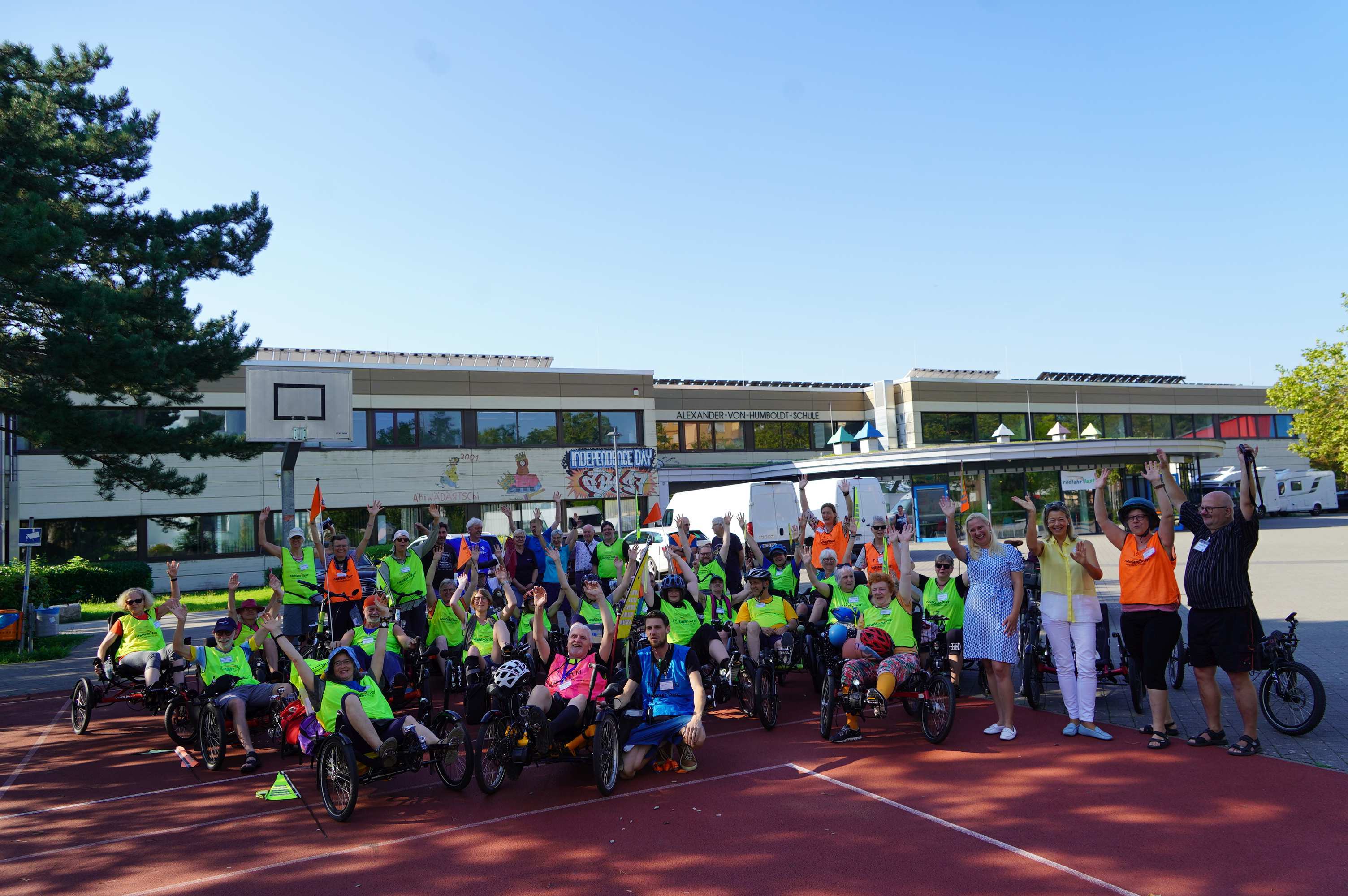 Die Erste Kreisbeigeordnete Diana Stolz steht gemeinsam mit den Teilnehmenden der diesjährigen Radfahrlust-Tour, dem Initiator Klaus Vock, der Vorsitzenden der DMSG LV Hessen Dagmar Spill und der Tour-Sprecherin Anke Vettel an dem Gemeinschaftsquartier in der Alexander-von-Humboldt-Schule Viernheim.