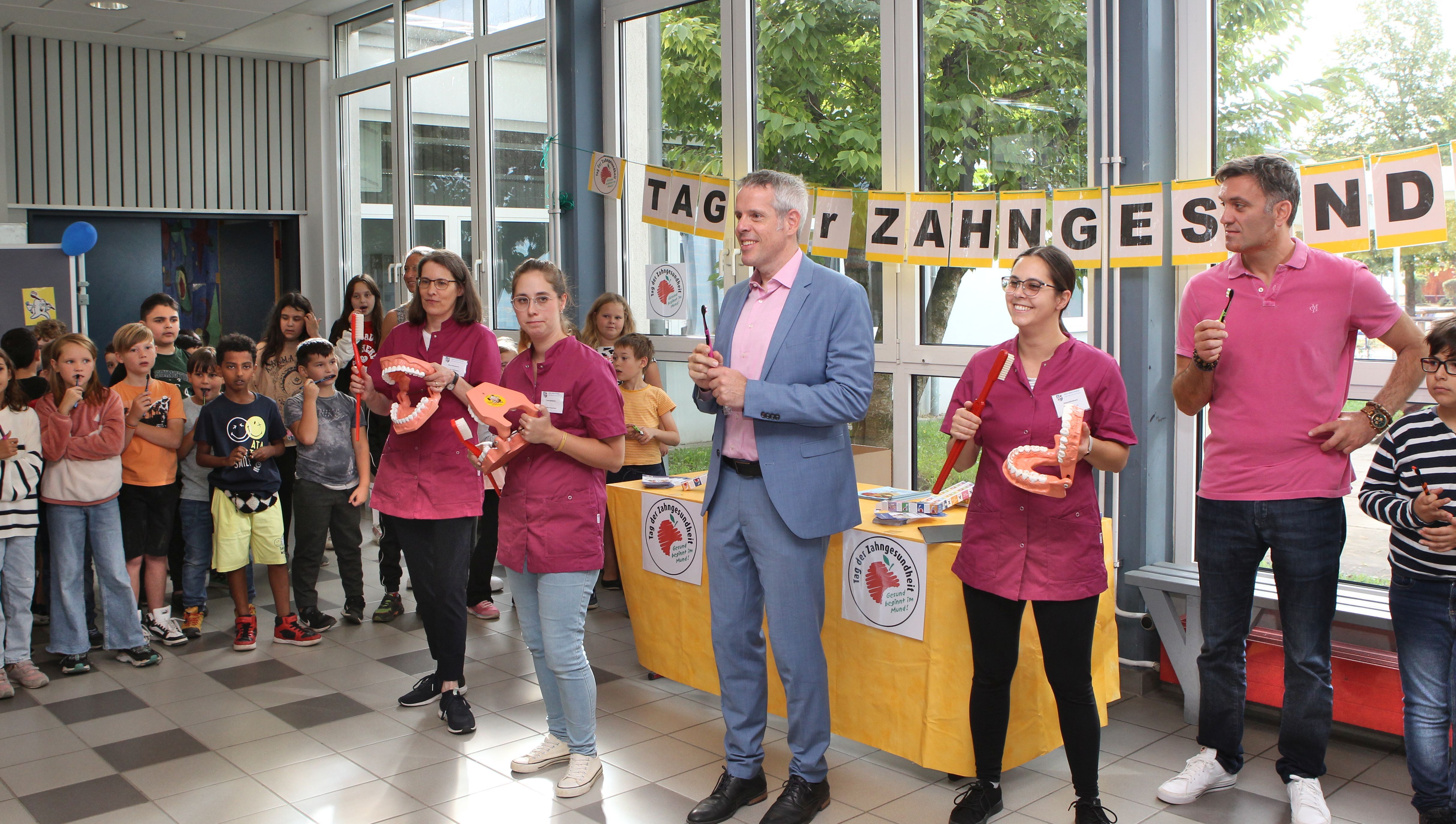 Landrat Christian Engelhardt (3. v. re.), der Leiter der Friedrich-Fröbel-Schule Viernheim Markus Taube (ganz rechts) und die Mitarbeiterinnen des Zahnärztlichen Dienstes des Bergsträßer Gesundheitsamtes übten mit den Drittklässlerinnen und Drittklässlern beim „Zahnputz-Rap“ das korrekte Zähneputzen.