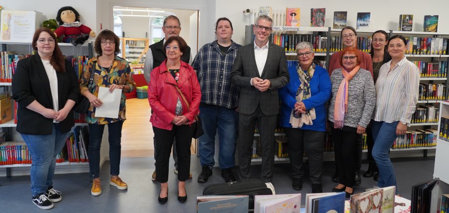 Landrat Christian Engelhardt steht gemeinsam mit den anwesenden Vertreterinnen und Vertretern der Bibliotheken des Kreises in der Stadtbücherei Zwingenberg.
