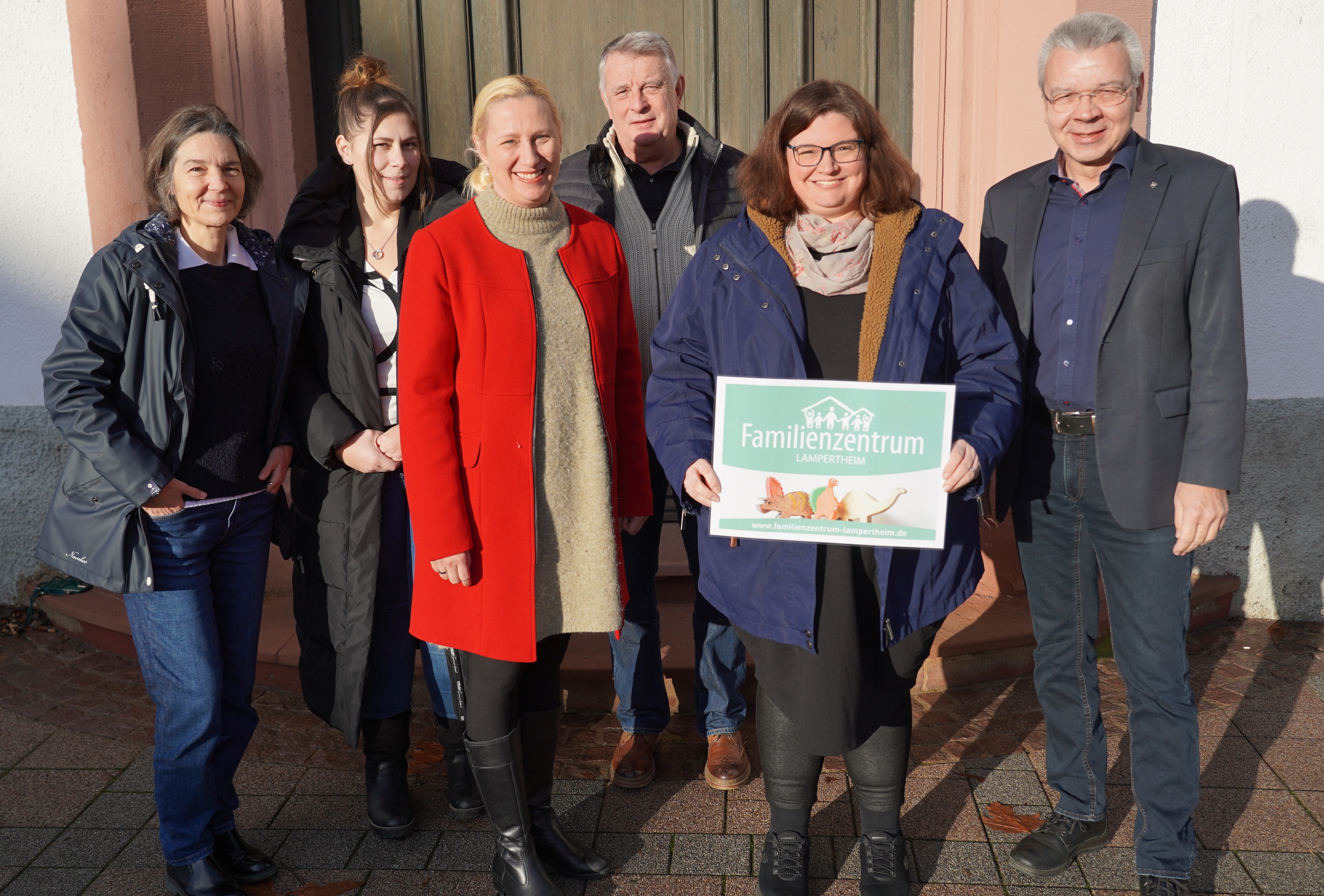 Die Erste Kreisbeigeordnete und Gesundheitsdezernentin Diana Stolz, die beiden PauLas für die Gemeinden im Ried (NORIE), Christina Adler-Schäfer und Michaela Weber, die Leiterin des Familienzentrums Lampertheim, Sabrina Mohr, der Übungsleiter vom Lampertheimer Lauftreff e.V., Jürgen Massonne sowie der Lampertheimer Bürgermeister Gottfried Störmer stehen vor dem Eingang des Lampertheimer Rathauses.