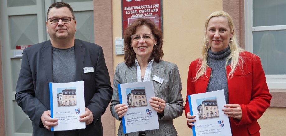 Die Erste Kreisbeigeordnete und Jugenddezernentin Diana Stolz (rechts), der Leiter des Bergsträßer Jugendamtes, Kai Kuhnert (links), und die Leiterin der Beratungsstelle für Eltern, Kinder und Jugendliche in Bensheim, Sybille Vonderschmidt-Viereck (Mitte) halten jeweils einen Jahresbericht 2022 in  den Händen.