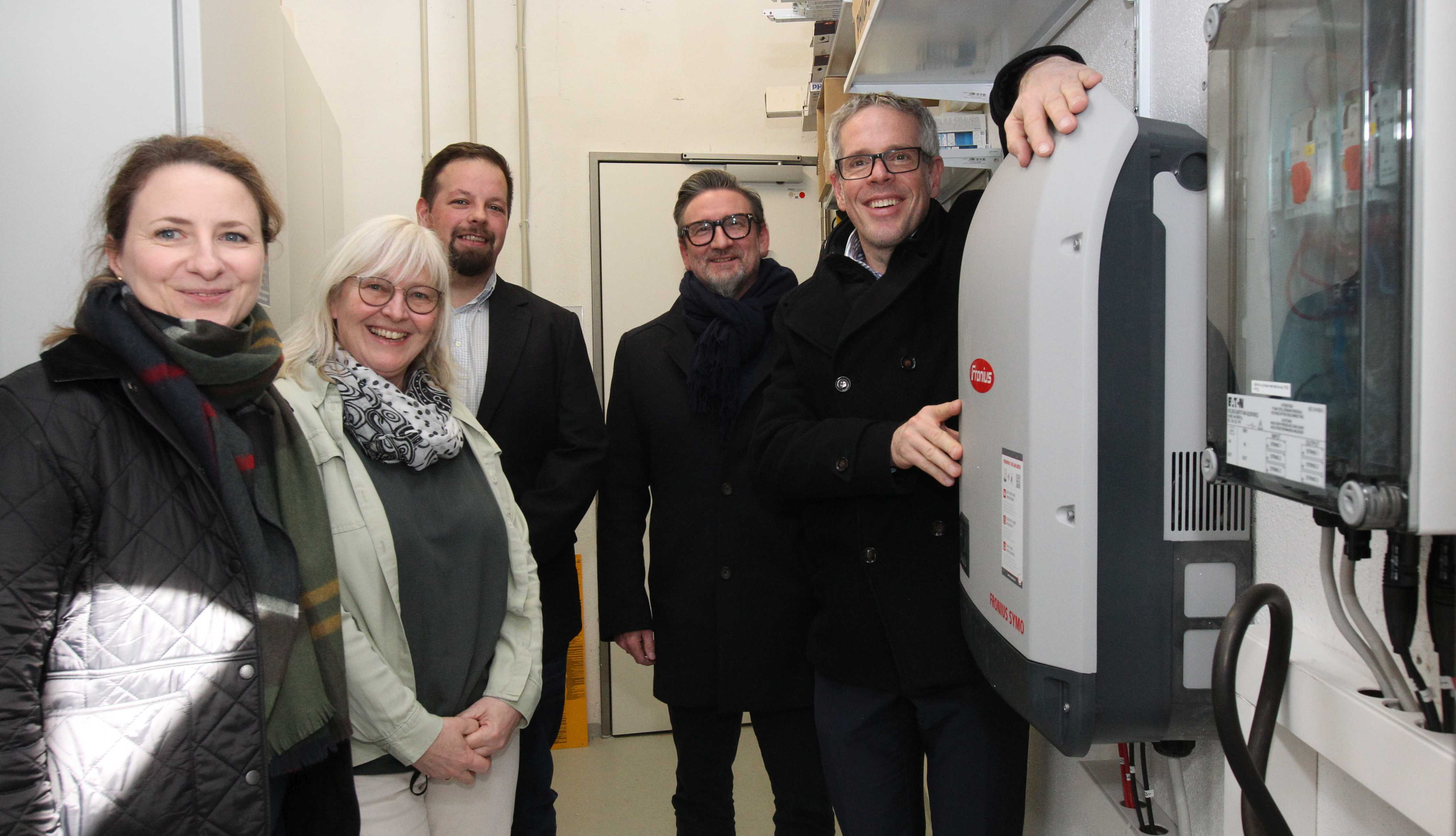 Landrat Christian Engelhardt steht gemeinsam mit der Schulleiterin der Seebergschule in Mörlenbach Petra Thobe, dem Bürgermeister Erik Kadesch, dem Geschäftsführer der Servicegesellschaft Bergstraße Marc Colin und der Fachfrau für Photovoltaik Myra Myhalnyuk neben der PV-Anlage in der Seebergschule Mörlenbach.