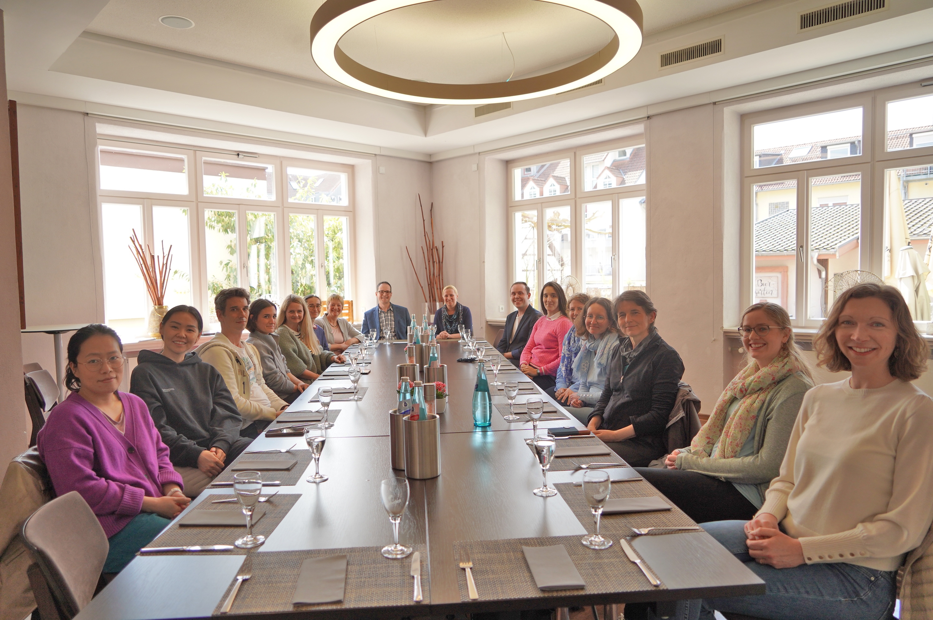 Die Erste Kreisbeigeordnete und Gesundheitsdezernentin Diana Stolz sitzt gemeinsam mit dem Vorsitzenden des Ärztenetzes Heppenheim, Dr. Jens Braun, der Referentin und Mitarbeiterin des Kompetenzzentrums Weiterbildung Hessen, Dr. Antje Erler und den Teilnehmenden des Landtages beim gemeinsamen Mittagessen in Heppenheim an einem langen, gedeckten Esstisch.