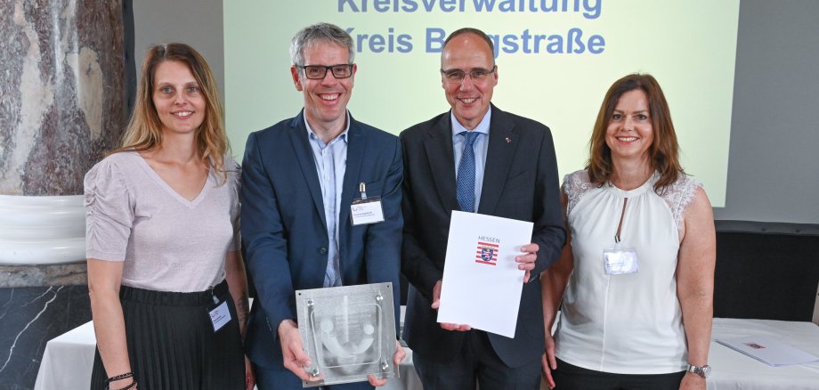 Landrat Christian Engelhardt und die zwei Frauen- und Gleichstellungsbeauftragten des Kreises Alexandra Schmitt  und Nicole Schmitt stehen gemeinsam mit Innenminister Peter Beuth im Schloss Biebrich und halten das Gütesiegel.