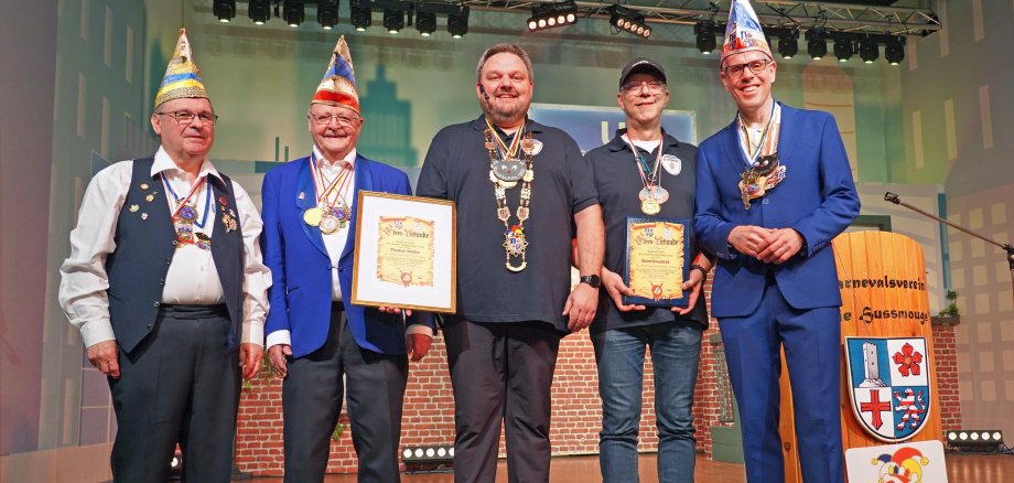 Landrat Christian Engelhardt (re.), Ulrich Knorr, Vize-Präsident der NiBa (Narren im besten Alter, 2. v. li.), und Siegmund Mendyk von NiBa (li.) überreichten die Kreisnarrenkette an den Ehrenpräsidenten des Aschbacher Karnevalvereins „Hussmouge“ Thomas Sattler (Mitte) und die Kreisnarren-Ehrenplakette an den „Hussmouge“-Vorsitzenden Horst Gramlich (2. v. re.).