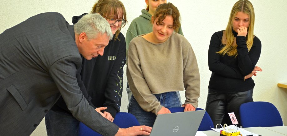 Jan Fuchs, Referent für digitale Bildung beim Kreis Bergstraße, zeigt beim STEAM-Workshop Schülerinnen etwas zu ihrem Lego-Robotics-Projekt auf einem Laptop.