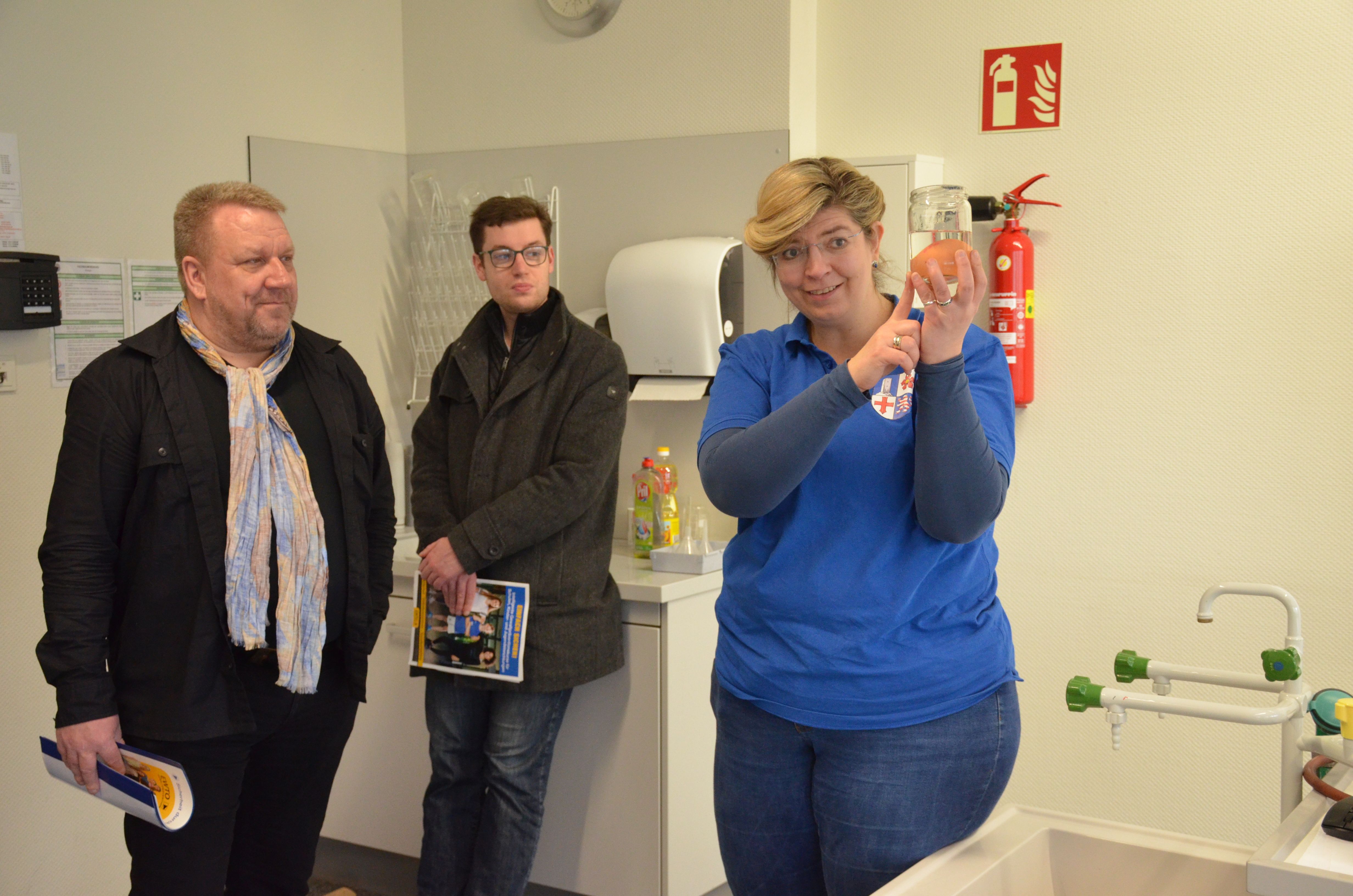 Ute Fuchs vom Bergsträßer Gesundheitsamt verdeutlichte im Workshop „Erste Hilfe“ mit Hilfe eines rohen Eis, wie empfindlich der Kopf auf Verletzungen reagiert. Der hauptamtliche Kreisbeigeordnete Matthias Schimpf und der erste Stadtrat der Stadt Lampertheim Marius Schmidt beobachten sie auf dem Bild dabei.