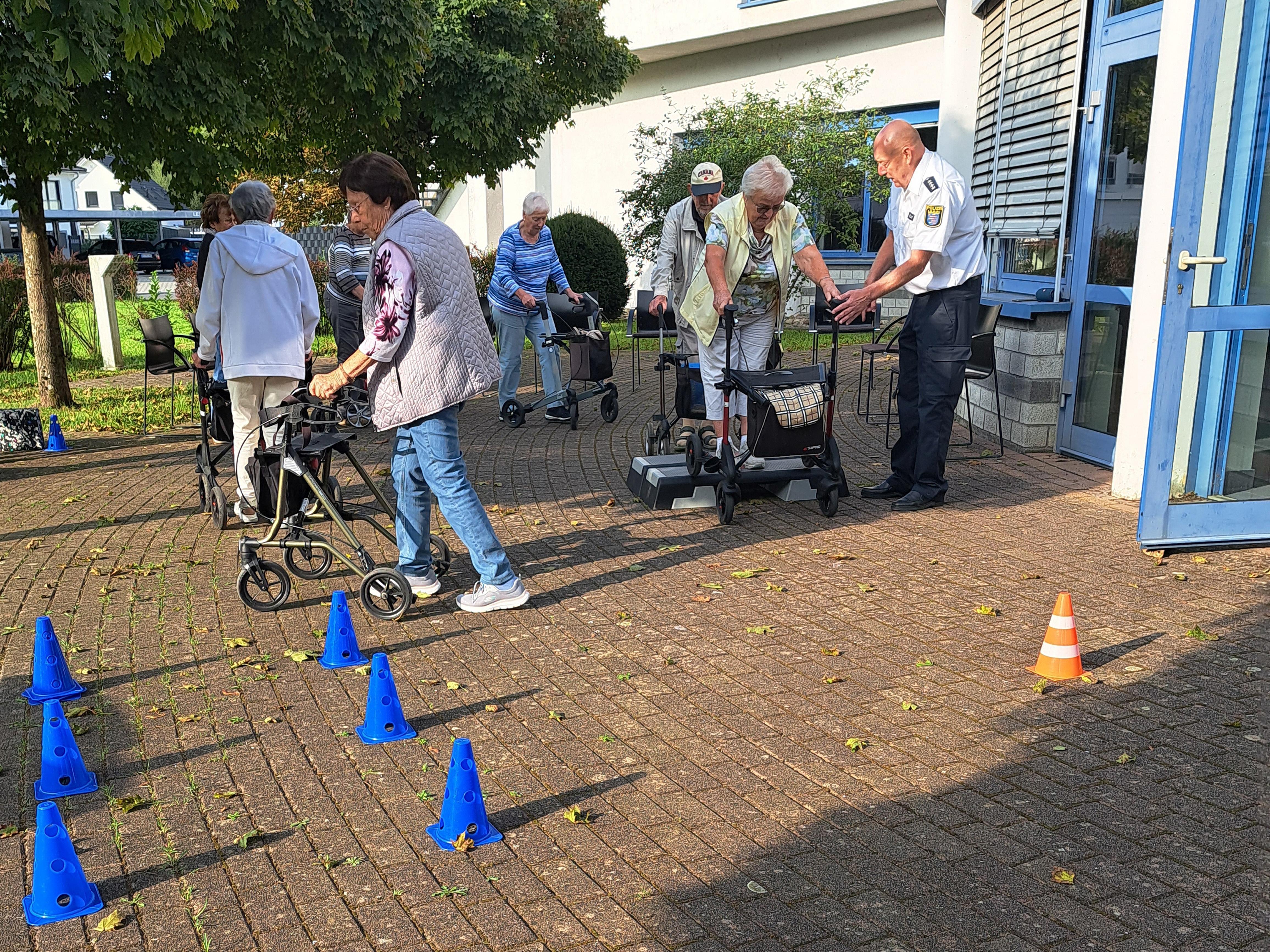 Der Vorsitzende der Kreisverkehrswacht Odenwald und Polizeihauptkommissar der Polizei Südhessen Ralf Drexelius (re.) – hier bei einem entsprechenden Kurs in Rimbach – gibt den Teilnehmerinnen und Teilnehmern des von den PauLas des Kreises Bergstraße organisierten Rollator-Trainings Tipps im Umgang mit den Gehhilfen.