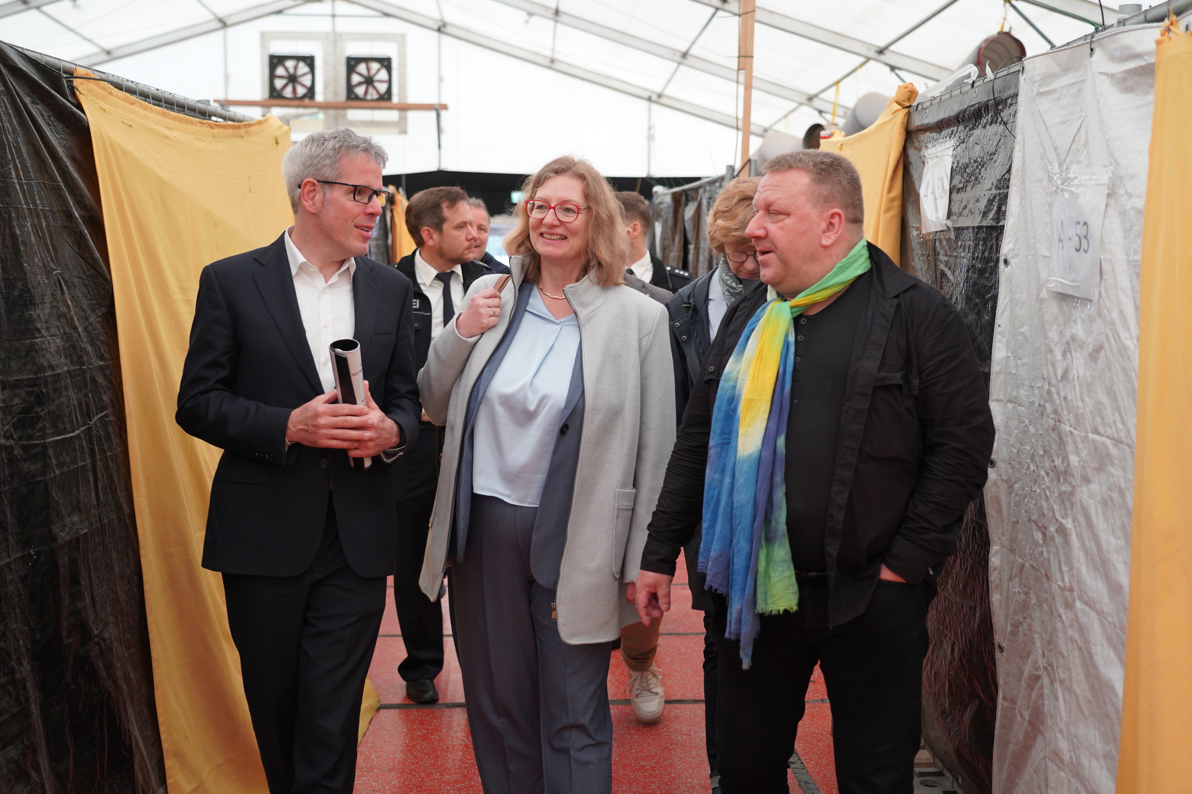 Landrat Christian Engelhardt (links) und der hauptamtliche Kreisbeigeordnete Matthias Schimpf (rechts) führen die Integrationsstaatssekretärin Katrin Hechler aus dem Hessischen Ministerium für Arbeit, Integration, Jugend und Soziales durch die Bensheimer Zeltstadt.