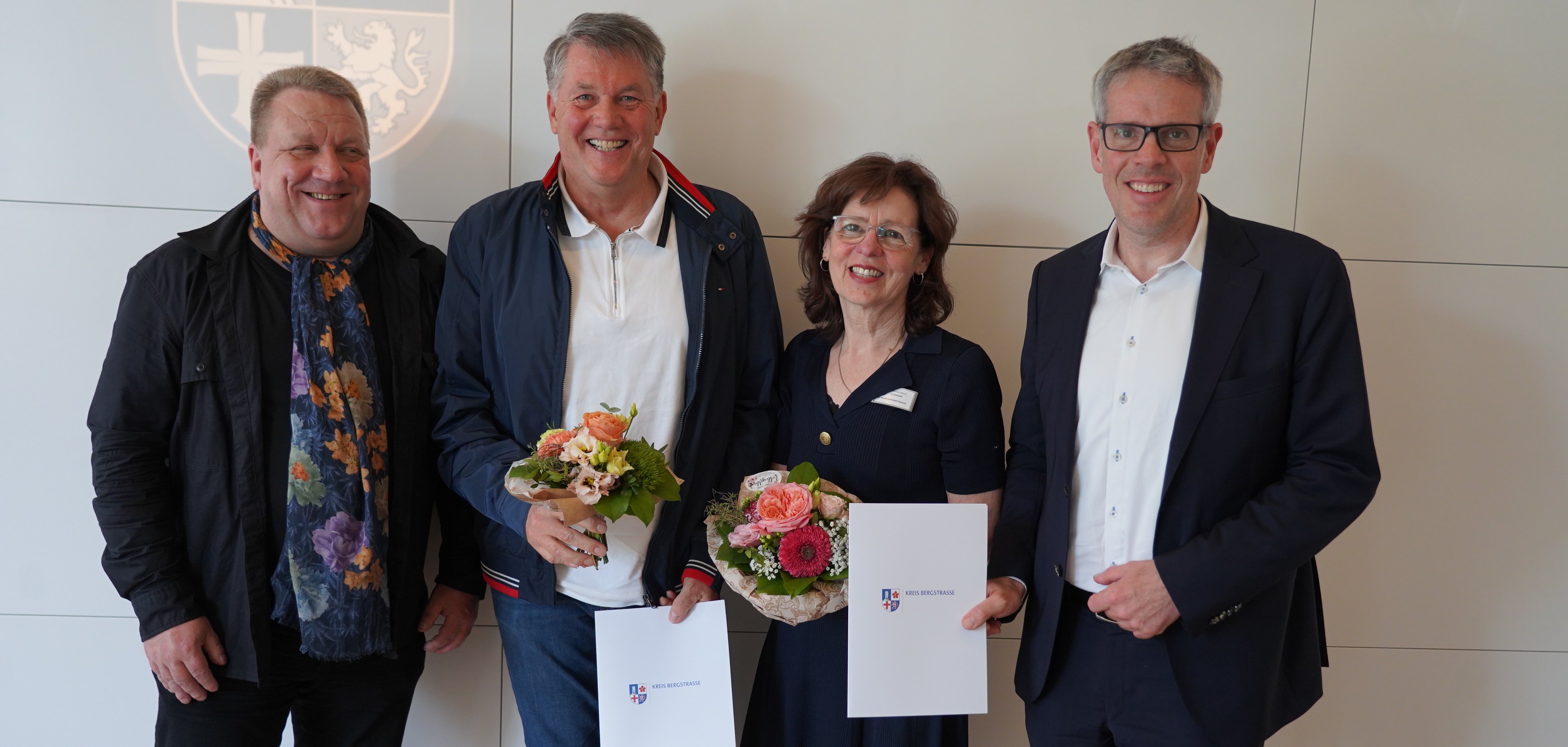 Landrat Christian Engelhardt, der hauptamtliche Kreisbeigeordnete Matthias Schimpf, die ehemalige Leiterin der Erziehungsberatungsstelle in Bensheim Sybille Vonderschmidt-Viereck, Thomas Unrath vom Eigenbetrieb Schule und Gebäudewirtschaft, der bei dem Termin ebenfalls verabschiedet wurde, stehen gemeinsam vor einer hellen Wand.