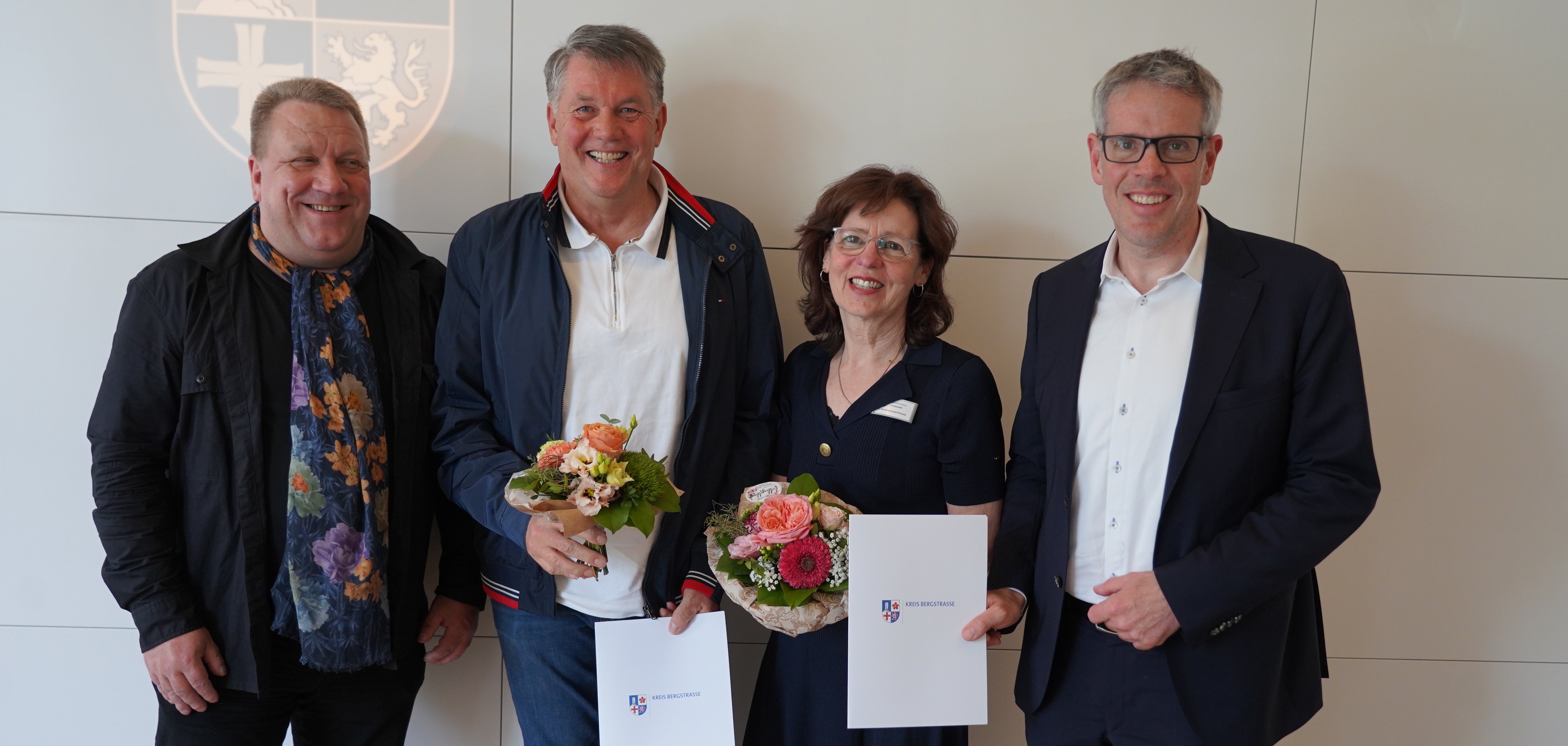 Landrat Christian Engelhardt, der hauptamtliche Kreisbeigeordnete Matthias Schimpf, die ehemalige Leiterin der Erziehungsberatungsstelle in Bensheim Sybille Vonderschmidt-Viereck, Thomas Unrath vom Eigenbetrieb Schule und Gebäudewirtschaft, der bei dem Termin ebenfalls verabschiedet wurde, stehen gemeinsam vor einer hellen Wand.