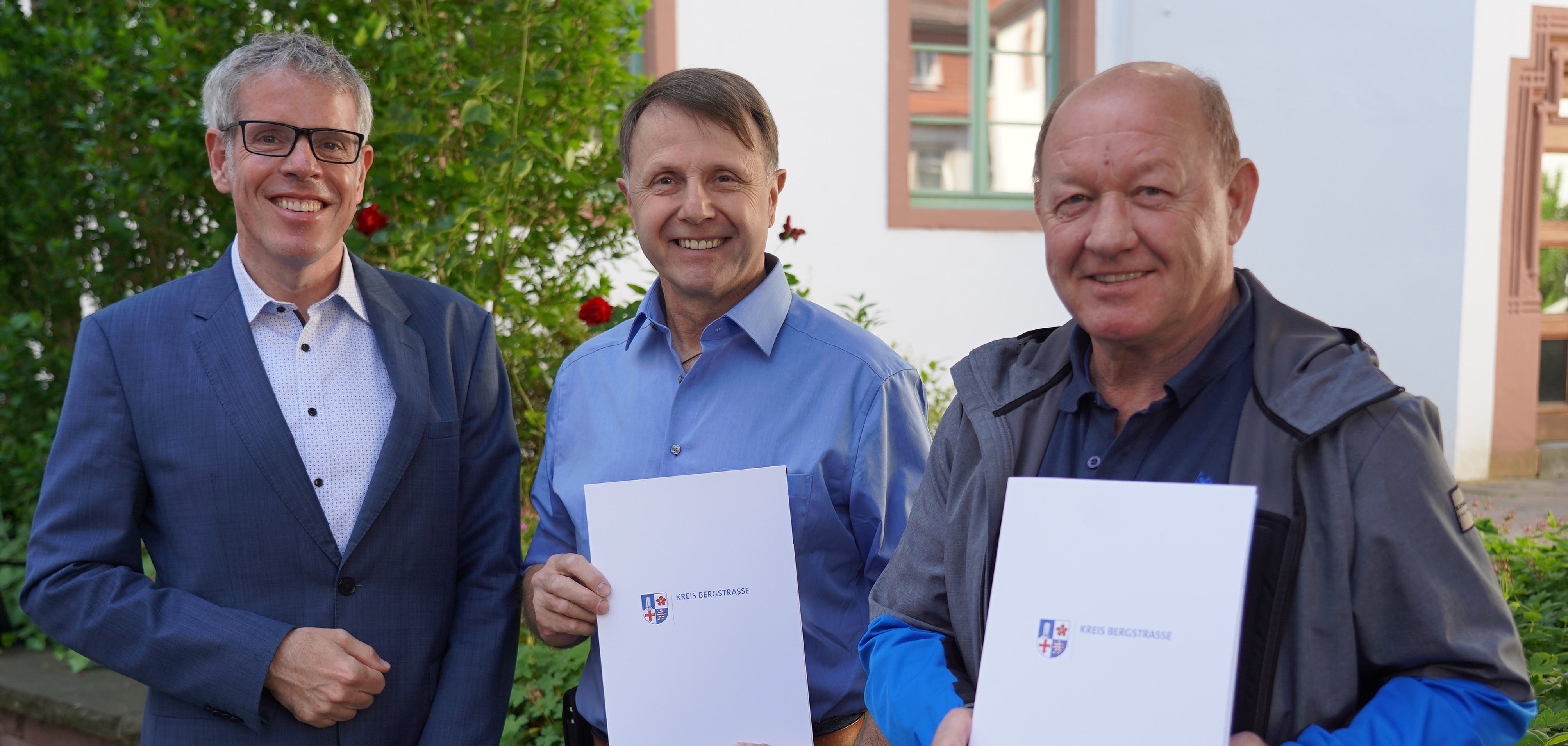 Landrat Christian Engelhardt (links) gratuliert den beiden Schulhausmeistern Markus Wecht (Mitte) von der Martin-Luther-Schule in Rimbach und Michael Schramm von der Werner-von-Siemens-Schule in Lorsch zum 25-jährigen Dienstjubiläum.