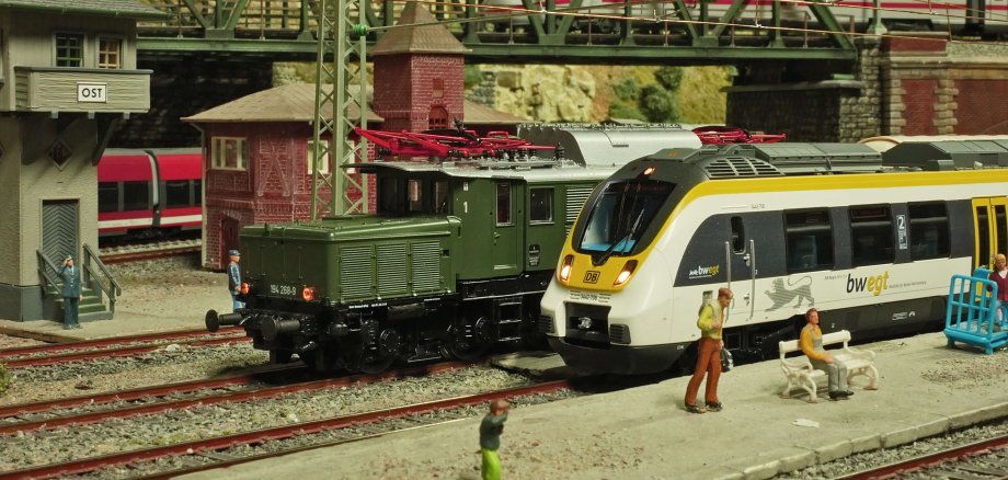 Ein paar Miniaturzüge stehen auf kleinen Gleisen.