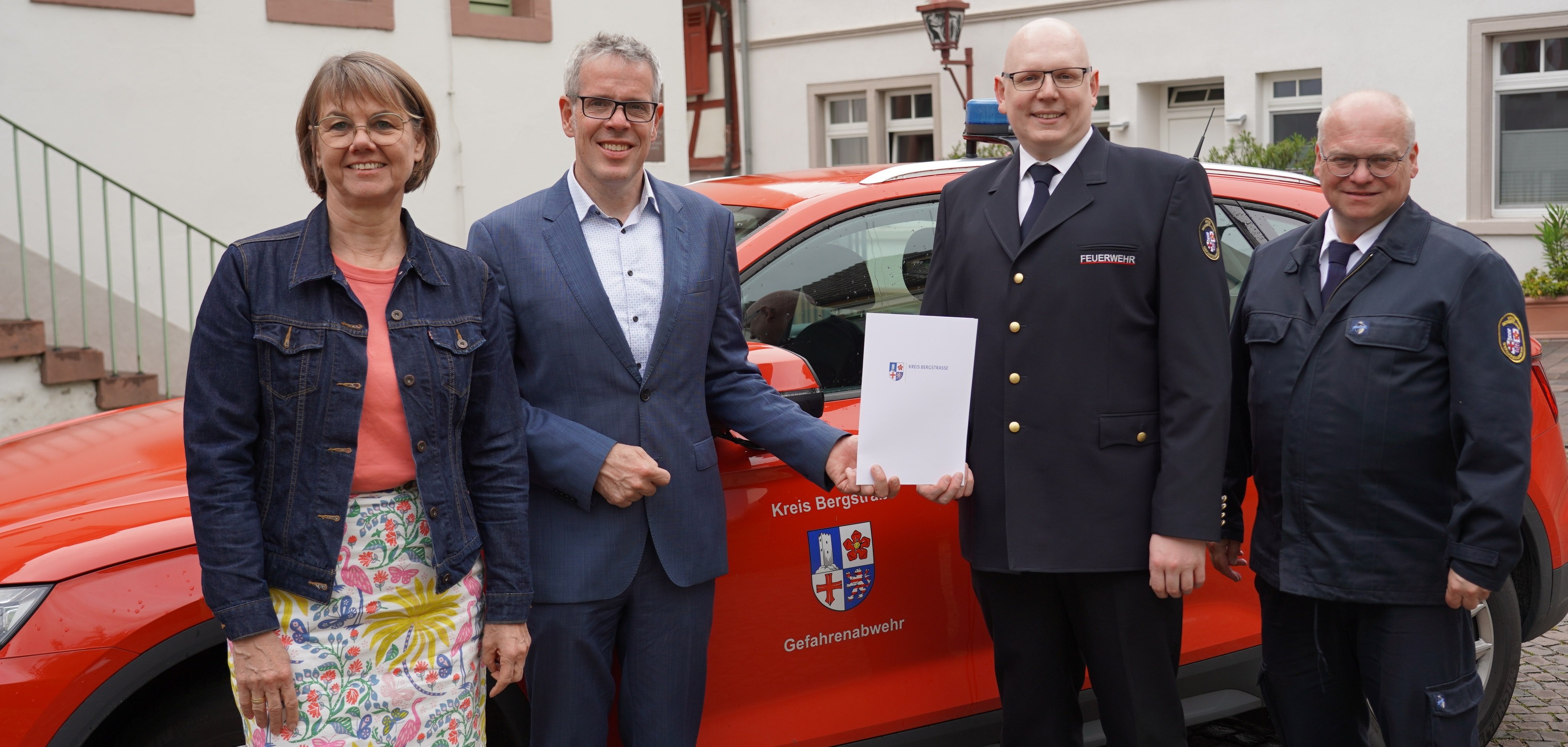 Landrat Christian Engelhardt steht gemeinsam mit der Leiterin der Abteilung Personalmanagement, Barbara Hoffbauer, dem Kreisbrandinspektor Steffen Lutter und dem neuen stellvertretenden Kreisbrandinspektor Markus Stracke vor einem Einsatzfahrzeug im Innenhof des Landratsamtes .