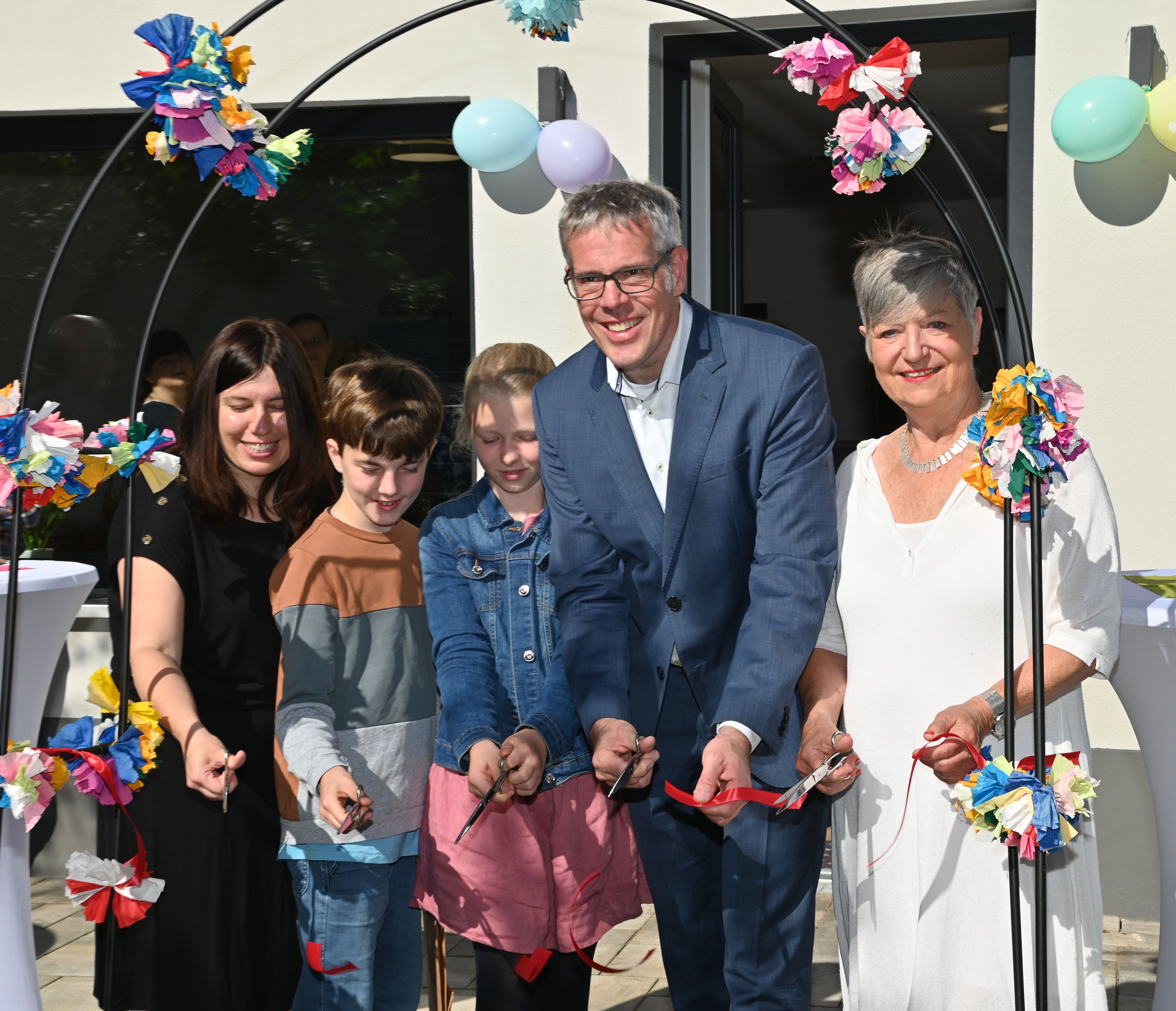 (v.l.n.r.) Schulleiterin Franziska Kaluza, stellvertretender Schulsprecher Benjamin Steinke, Schulsprecherin Marei Sowa, Landrat Christian Engelhardt und Bürgermeisterin Christine Klein schneiden das rote Band zur offiziellen Eröffnung der neuen Mensa der Hemsbergschule durch.