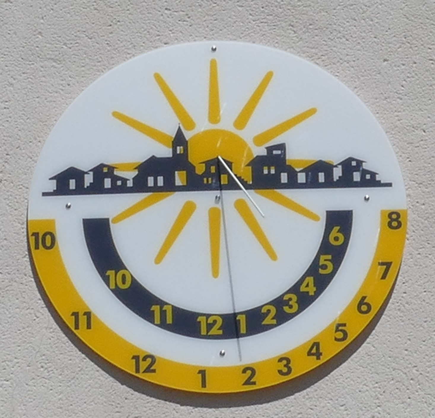 Ein gelb-schwarze Sonnenuhr hängt an einer Wand.