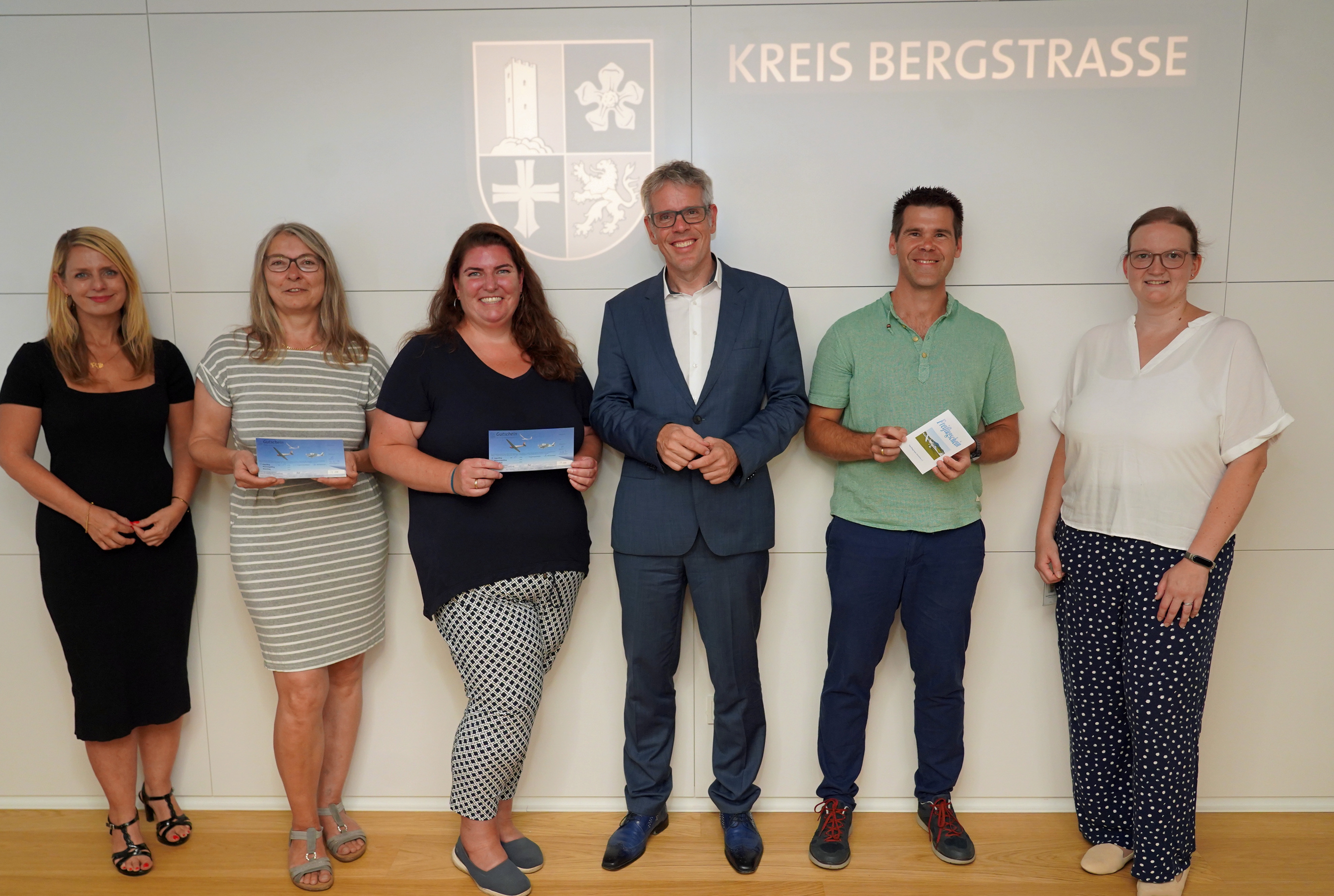 Landrat Christian Engelhardt (3.v.re.) überreicht den drei Gewinnerinnen und Gewinnern Dr. Sandra Thullner, Katharina Becker, Oliver Jägle (v.l.n.r., mit den Gutscheinen in der Hand) im Rahmen der Bergsträßer Bildungsumfrage ihre Segelflug-Gutscheine. Mit dabei: Corinna Simeth, Leiterin der Abteilung Grundsatz und Kreisentwicklung beim Kreis (ganz links) sowie Barbara Meyer, Sachbearbeiterin im Fachbereich Bildung der Kreisverwaltung (ganz rechts).