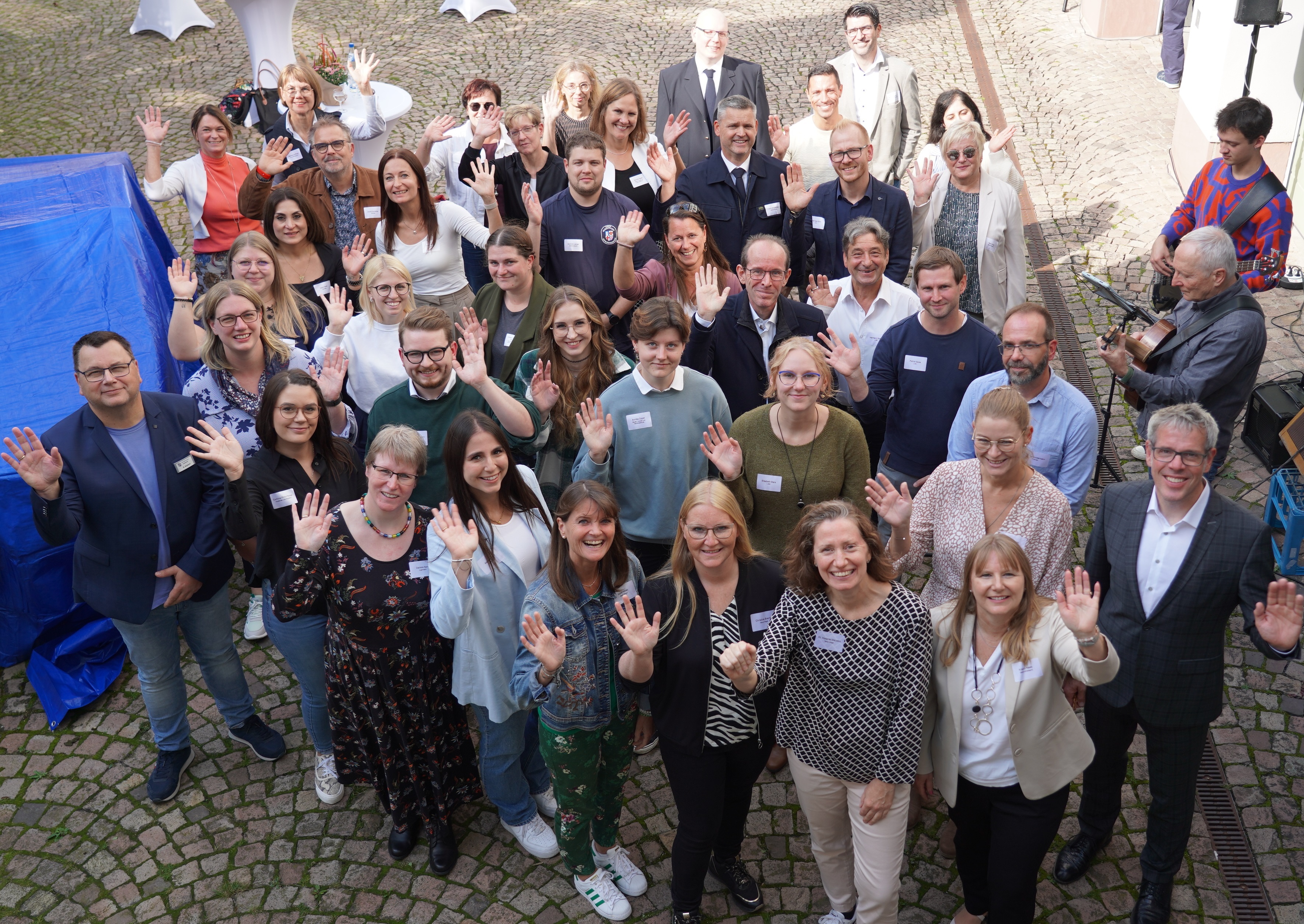 Landrat Christian Engelhardt und allen Geehrten sowie die entsprechenden Abteilungsleiterinnen und -leitern stehen im Hof der Kreisverwaltung und winken nach oben in die Kamera.