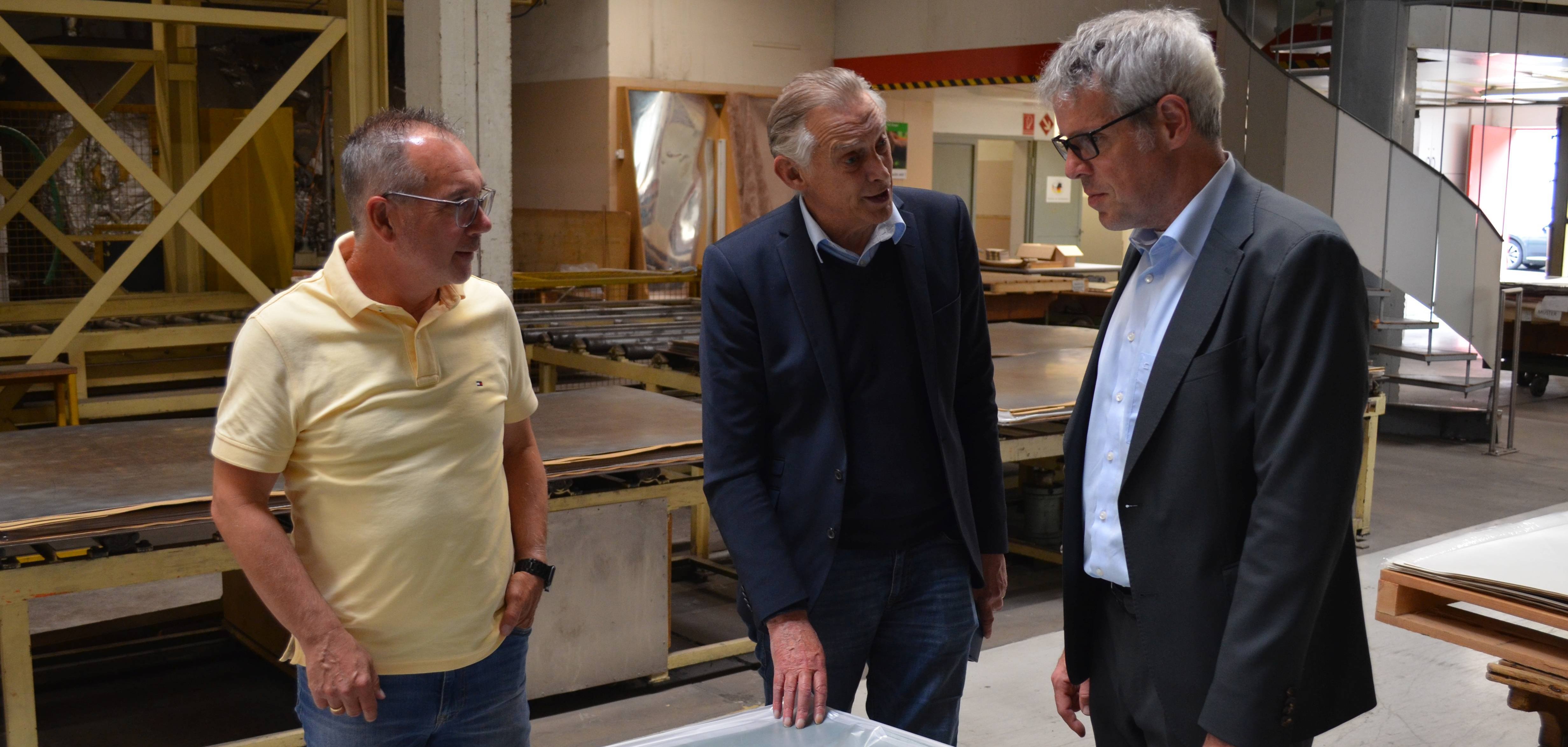 Die beiden Geschäftsführer Holger Obländer und Rolf van den Berg erklären Landrat Christian Engelhardt am Beispiel einer Tischkicker-Oberfläche wie die Funktionalisierung ihrer Platten realisiert wird.