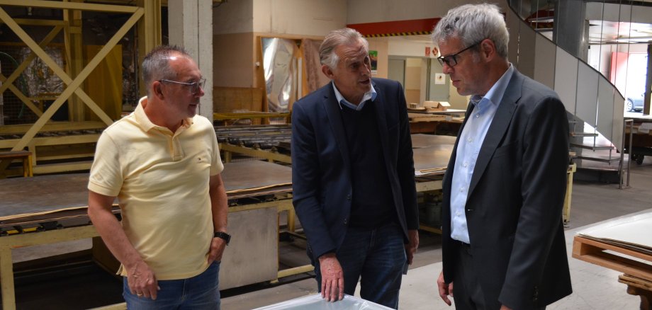 Die beiden Geschäftsführer Holger Obländer und Rolf van den Berg erklären Landrat Christian Engelhardt am Beispiel einer Tischkicker-Oberfläche wie die Funktionalisierung ihrer Platten realisiert wird.