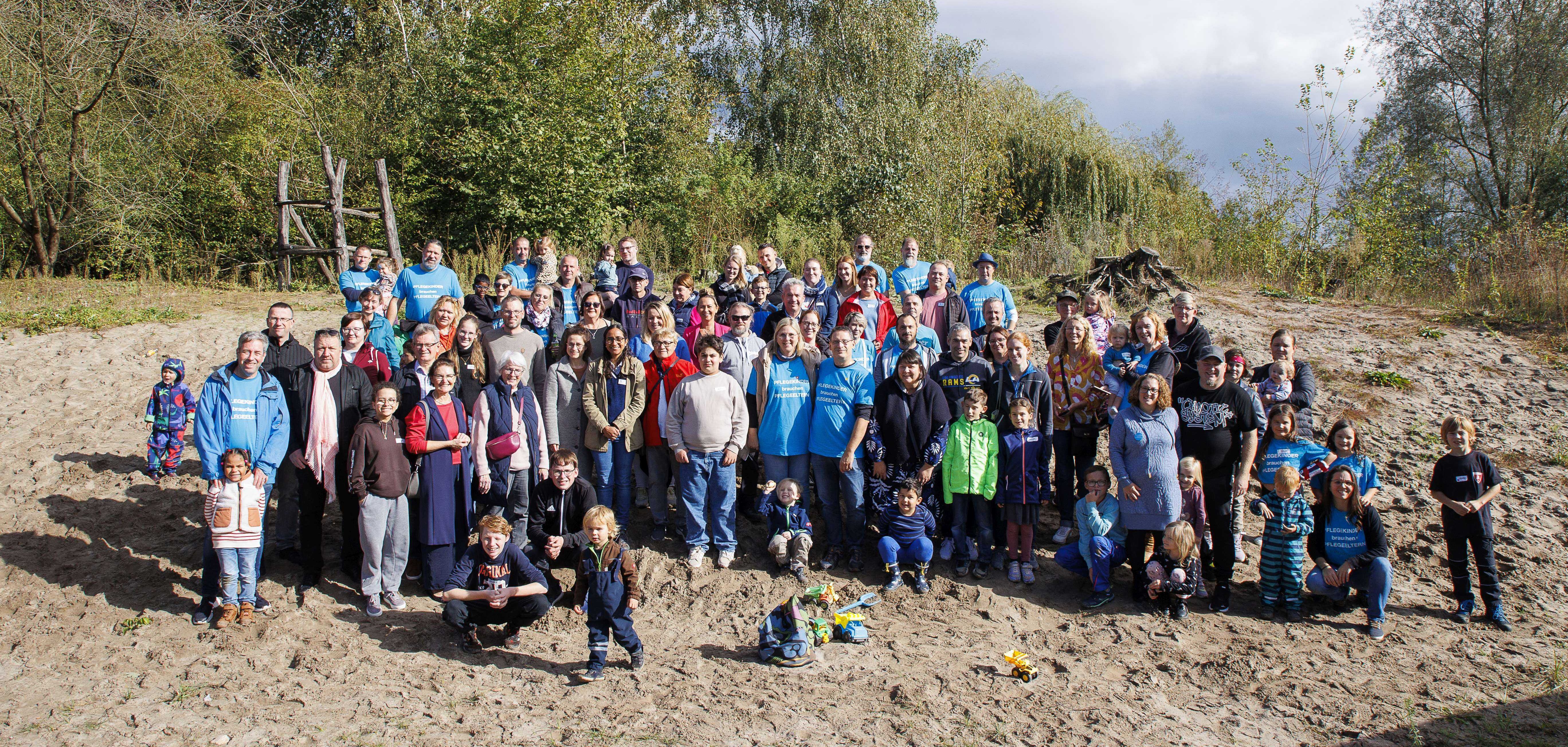 Der hauptamtliche Kreisbeigeordnete Matthias Schimpf steht mit Pflegefamilien und Pflegekindern sowie Mitarbeiterinnen und Mitarbeitern des Bergsträßer Jugendamtes beim Pflegefamilienfest auf dem Hof des Naturschutzzentrums Bensheim.