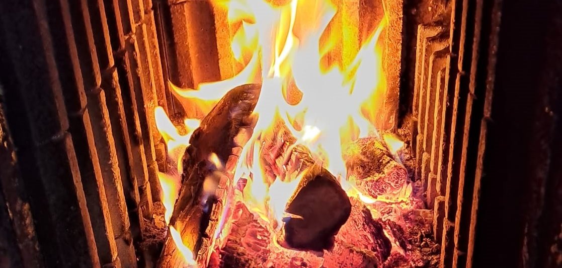 Ein Feuer brennt hinter einem Kaminfenster.