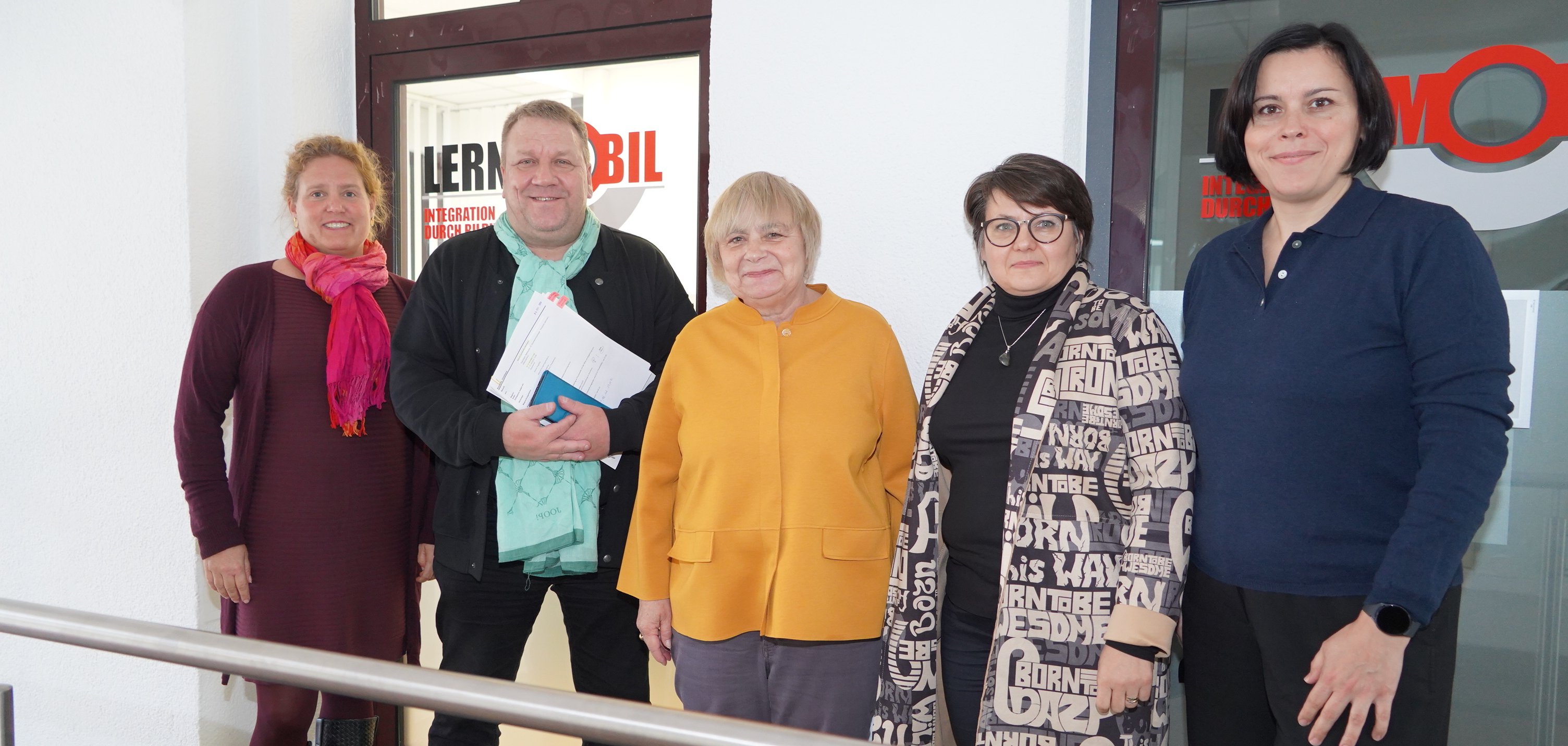 Der hauptamtliche Kreisbeigeordnete Matthias Schimpf steht mit der Vereinsgründerin Dr. Brigitta Eckert, der Geschäftsführerin Larysa Kay-Kulakowski, der Leiterin des Fachbereichs Sprache und Arbeitsmarktintegration, Dr. Oxana Berduta sowie der Leiterin der Stabstelle Vielfalt, Tina Koch vor dem Gebäude des Lernmobils Viernheim.